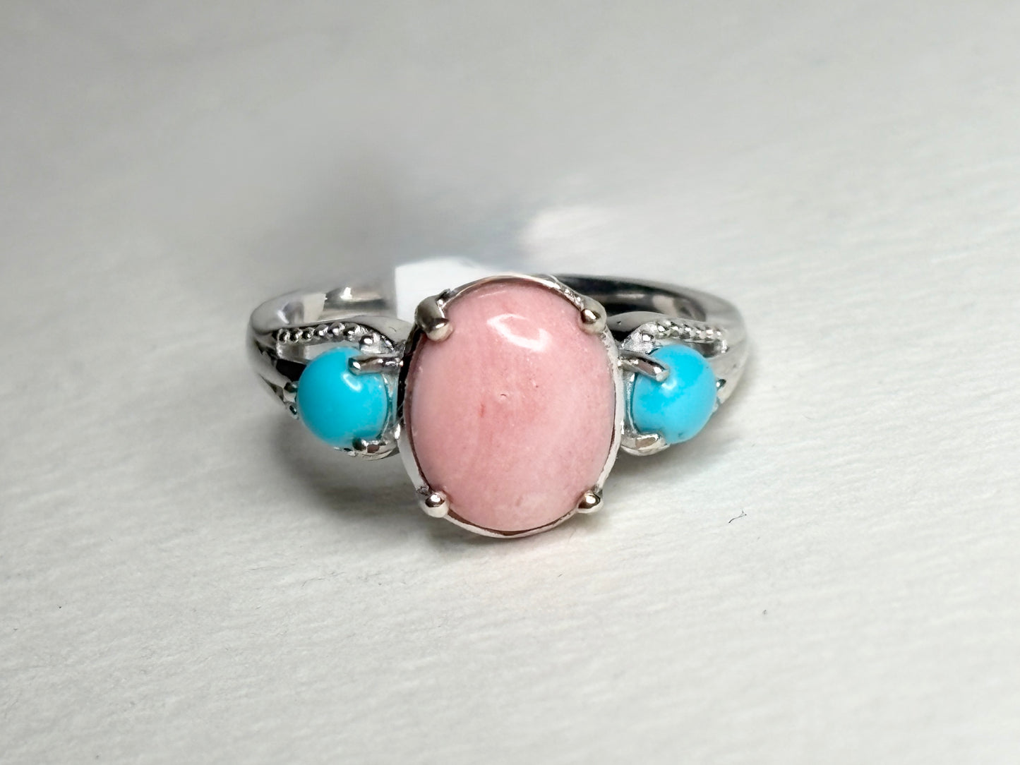 Sterling silver ring with oval peach opal and two round turquoise cabochons.
