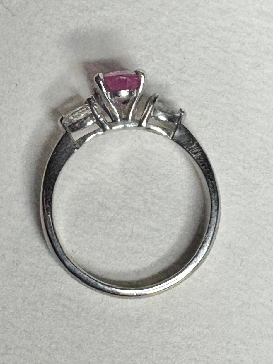 Platinum ring with a pink sapphire and two pear-shaped diamonds.