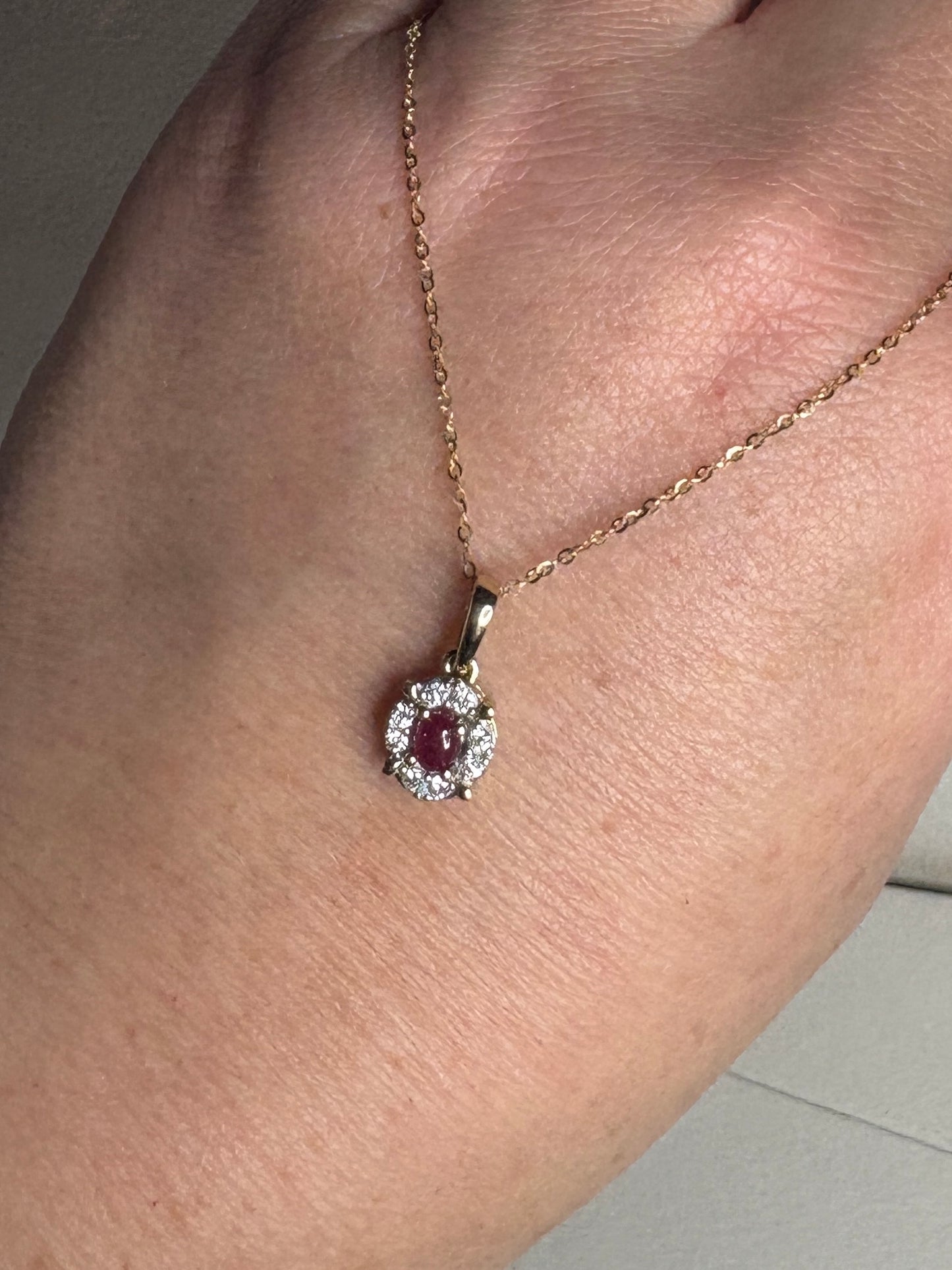 A delicate gold necklace with a ruby and diamond pendant.