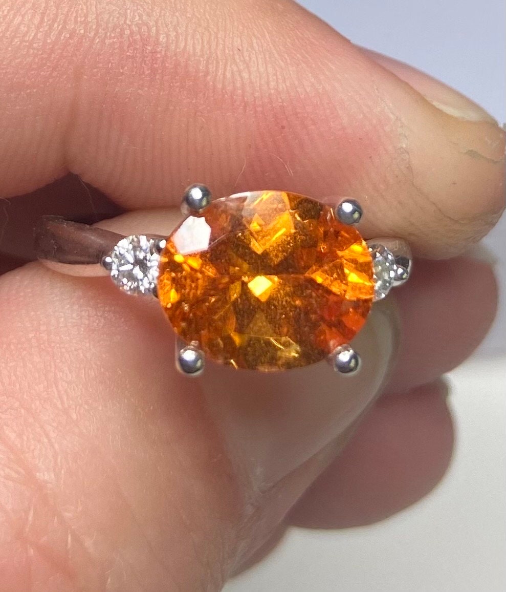 Sterling silver ring with oval spessartite garnet and two lab-grown diamonds.