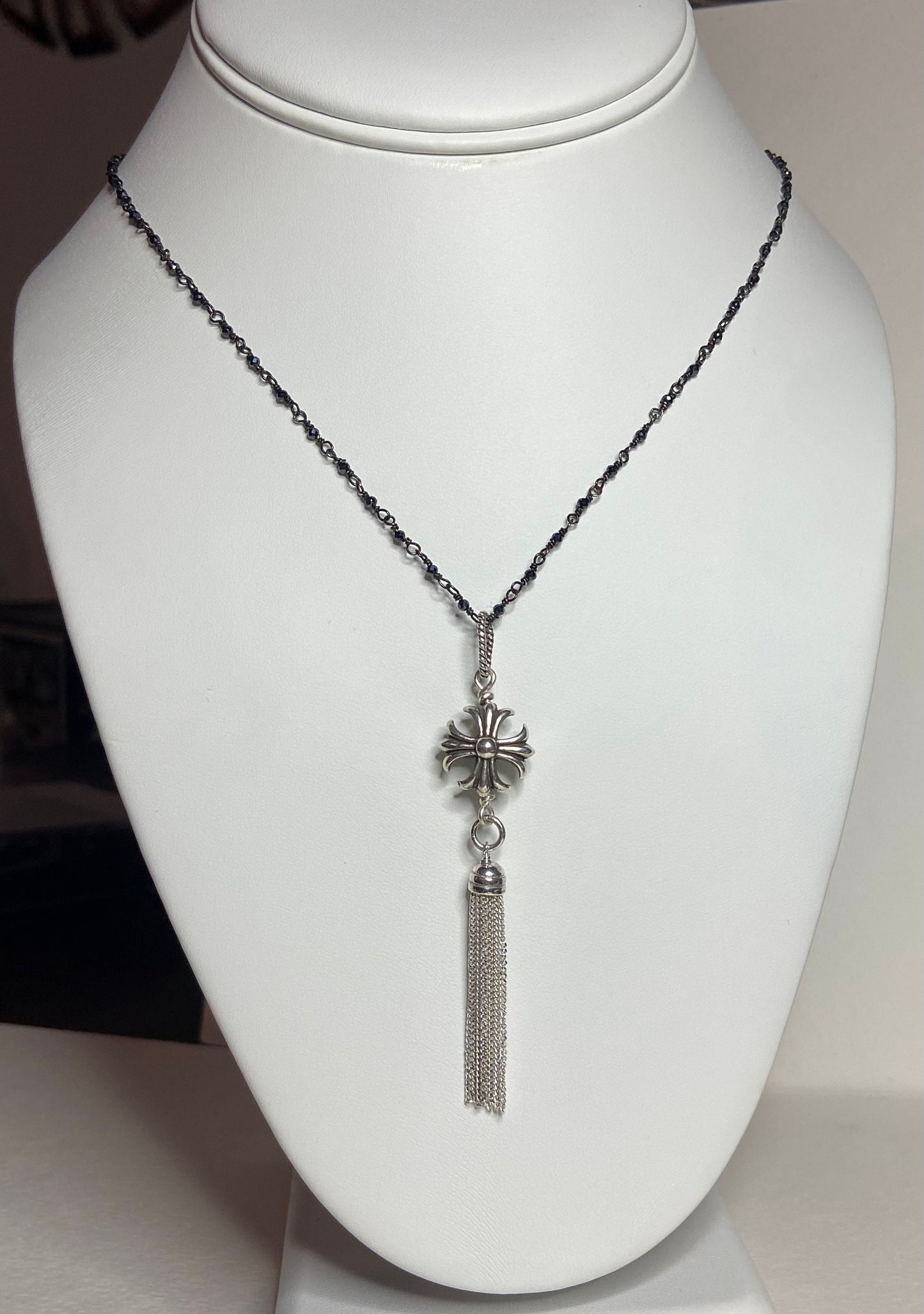 Sterling silver cross pendant with a tassel on a beaded chain.