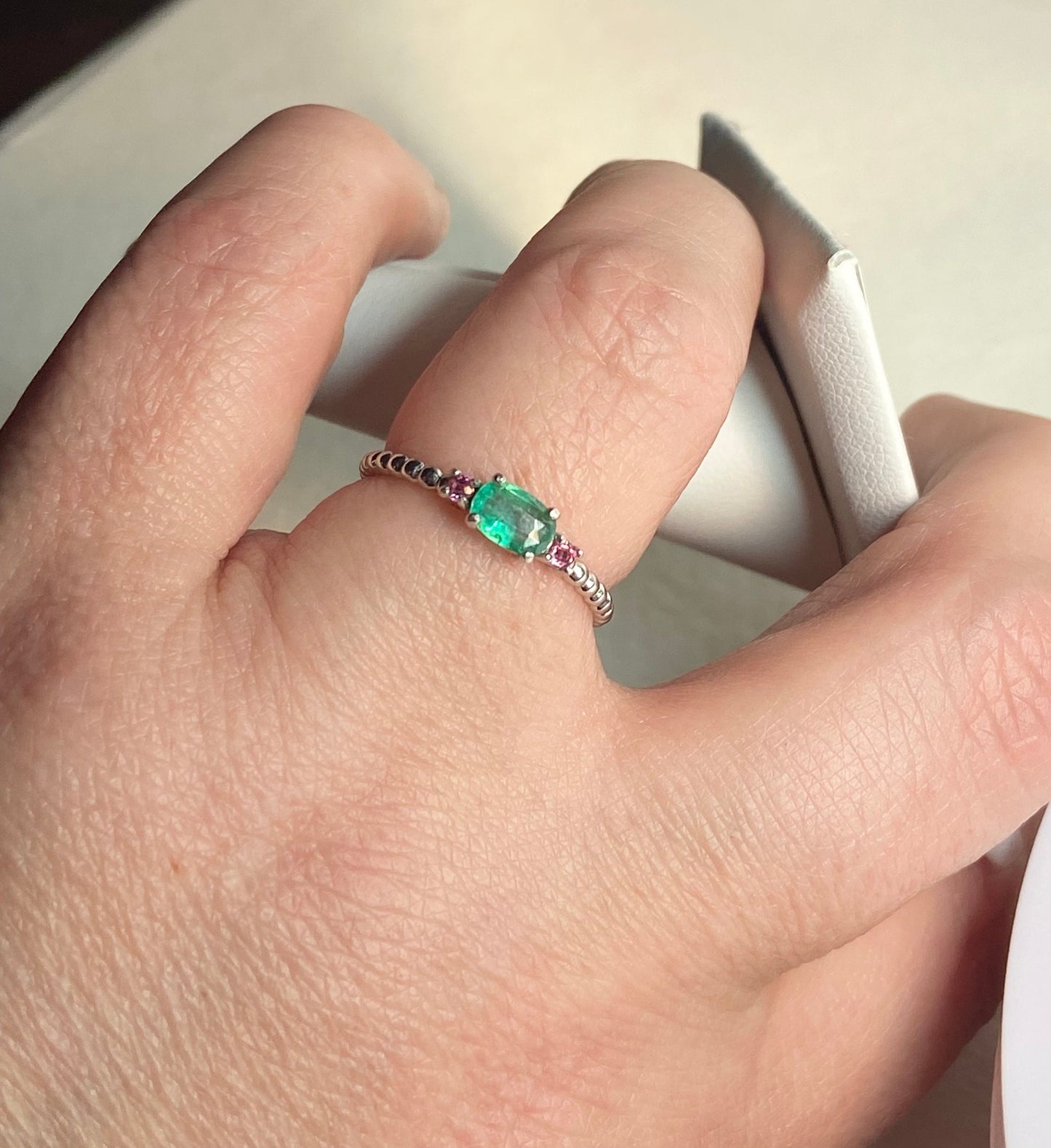 Sterling silver ring with an oval emerald and two red bixbite stones.