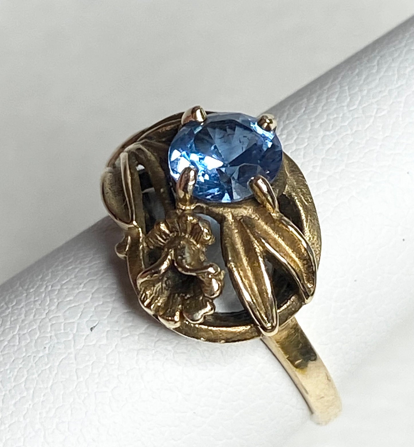 Art Nouveau style 10k yellow gold ring with a blue synthetic spinel and floral accents.