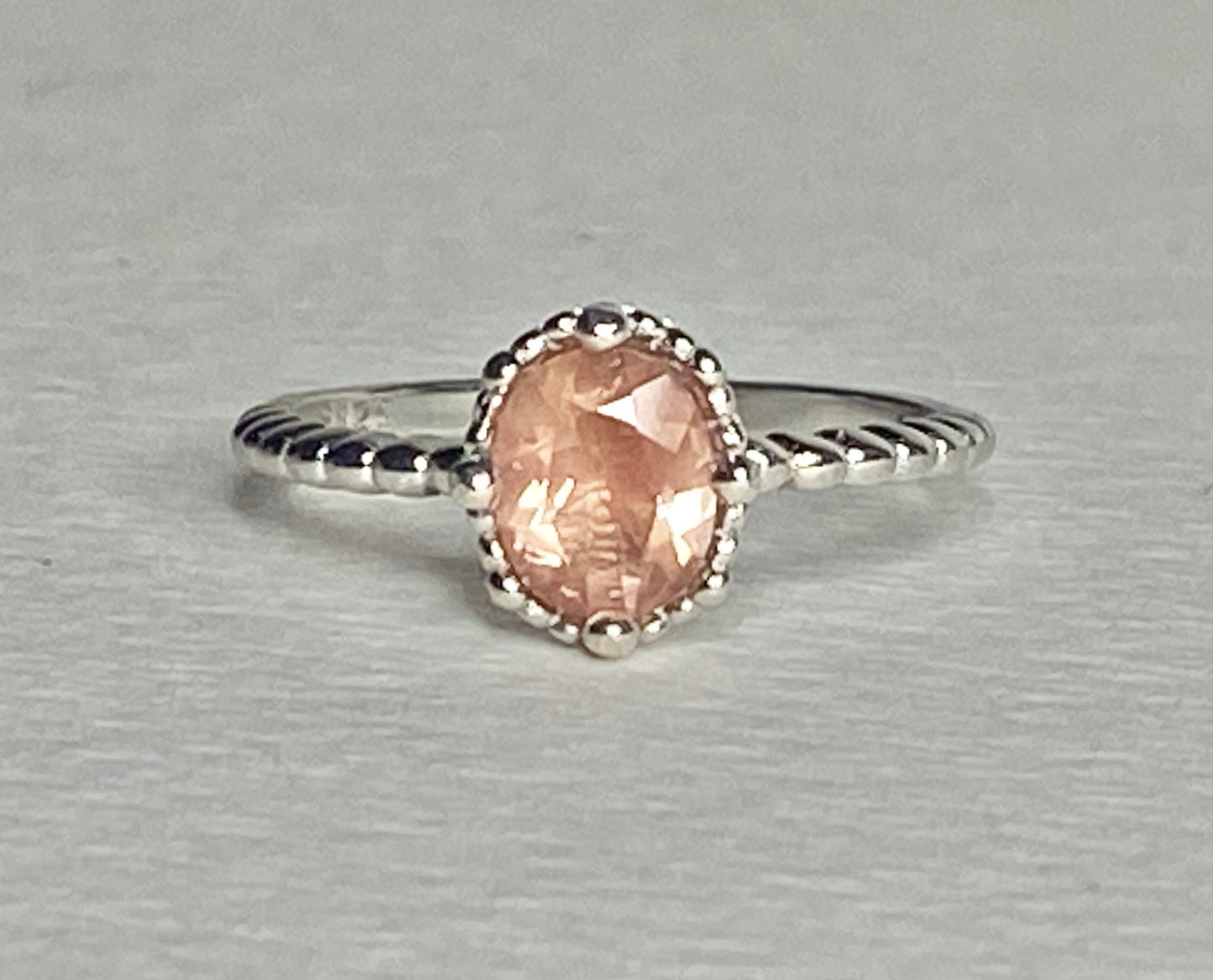 Sterling silver ring with a peach oval sunstone and beaded details.