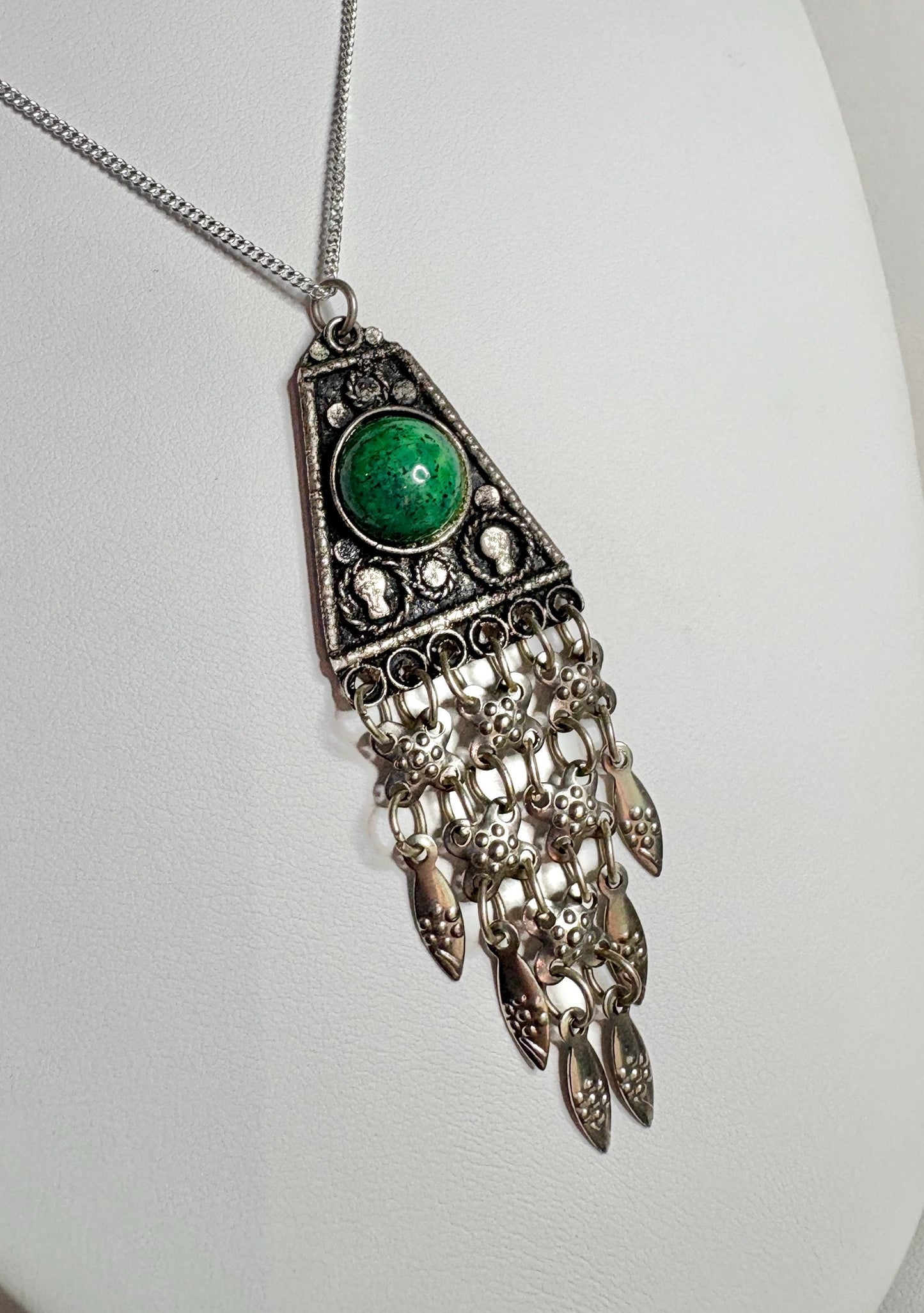 Sterling silver pendant with green stone and dangling fringe.
