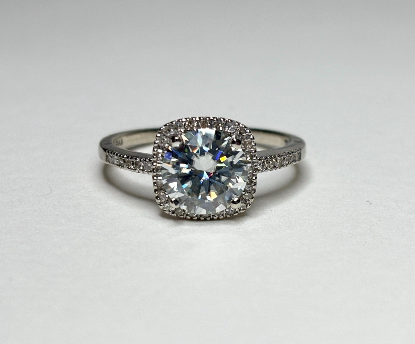 A 10k white gold ring with a large moissanite center stone surrounded by small diamonds.