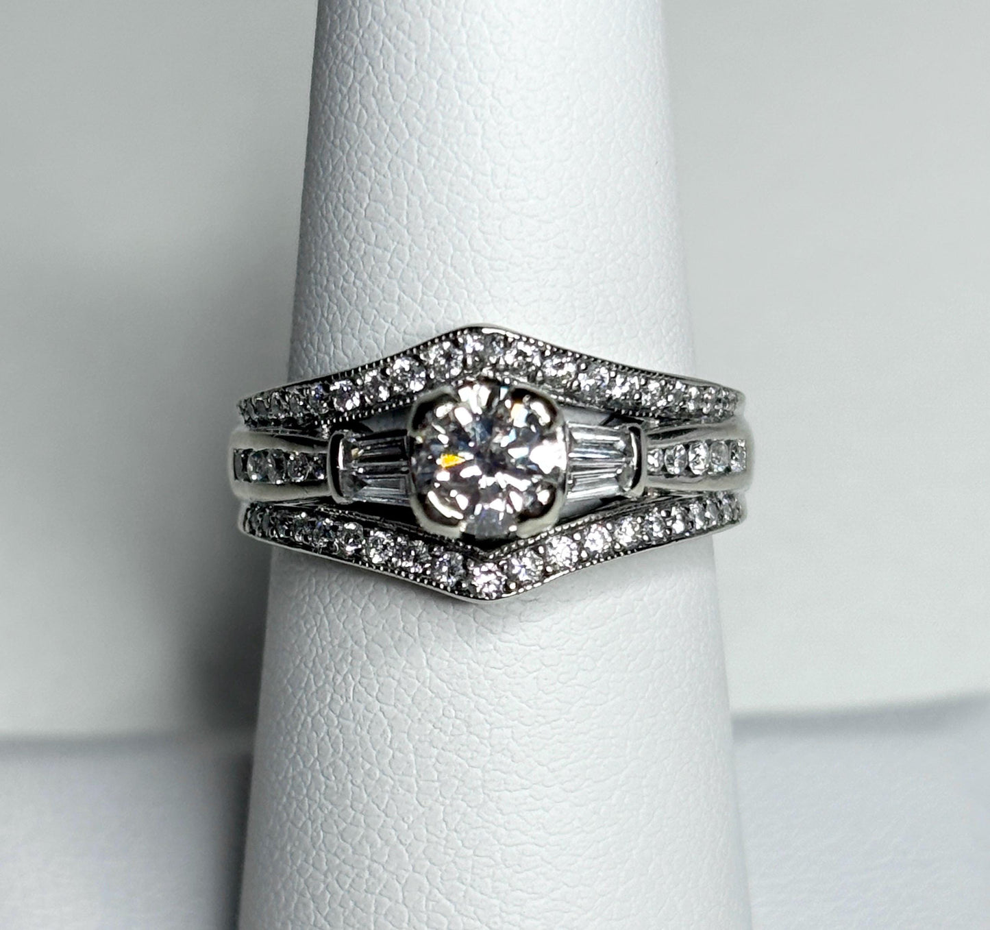 A 14k white gold engagement ring set with a round center diamond and baguette and round accent diamonds.