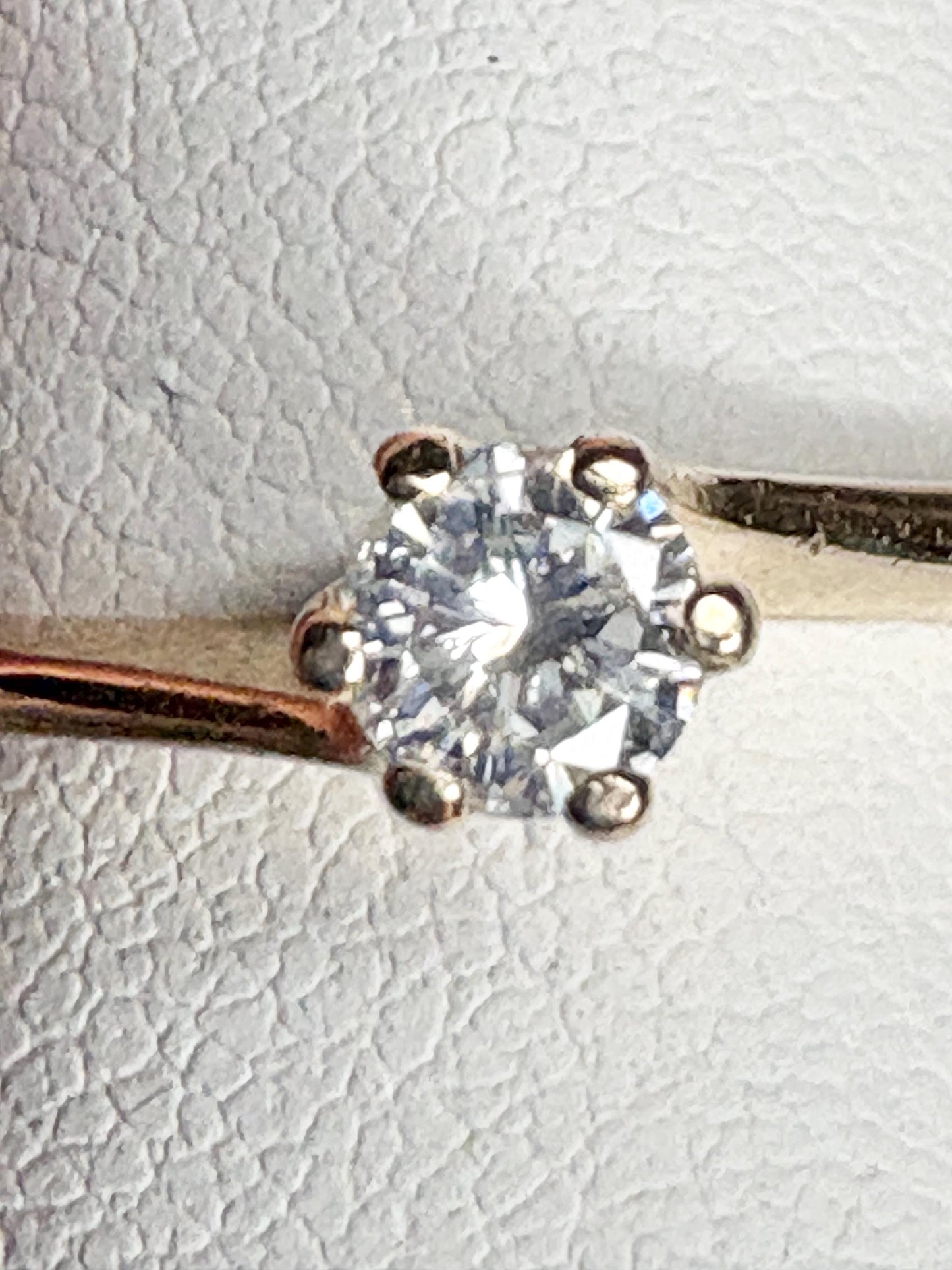 A solitaire diamond ring with a twist design in 14k gold.