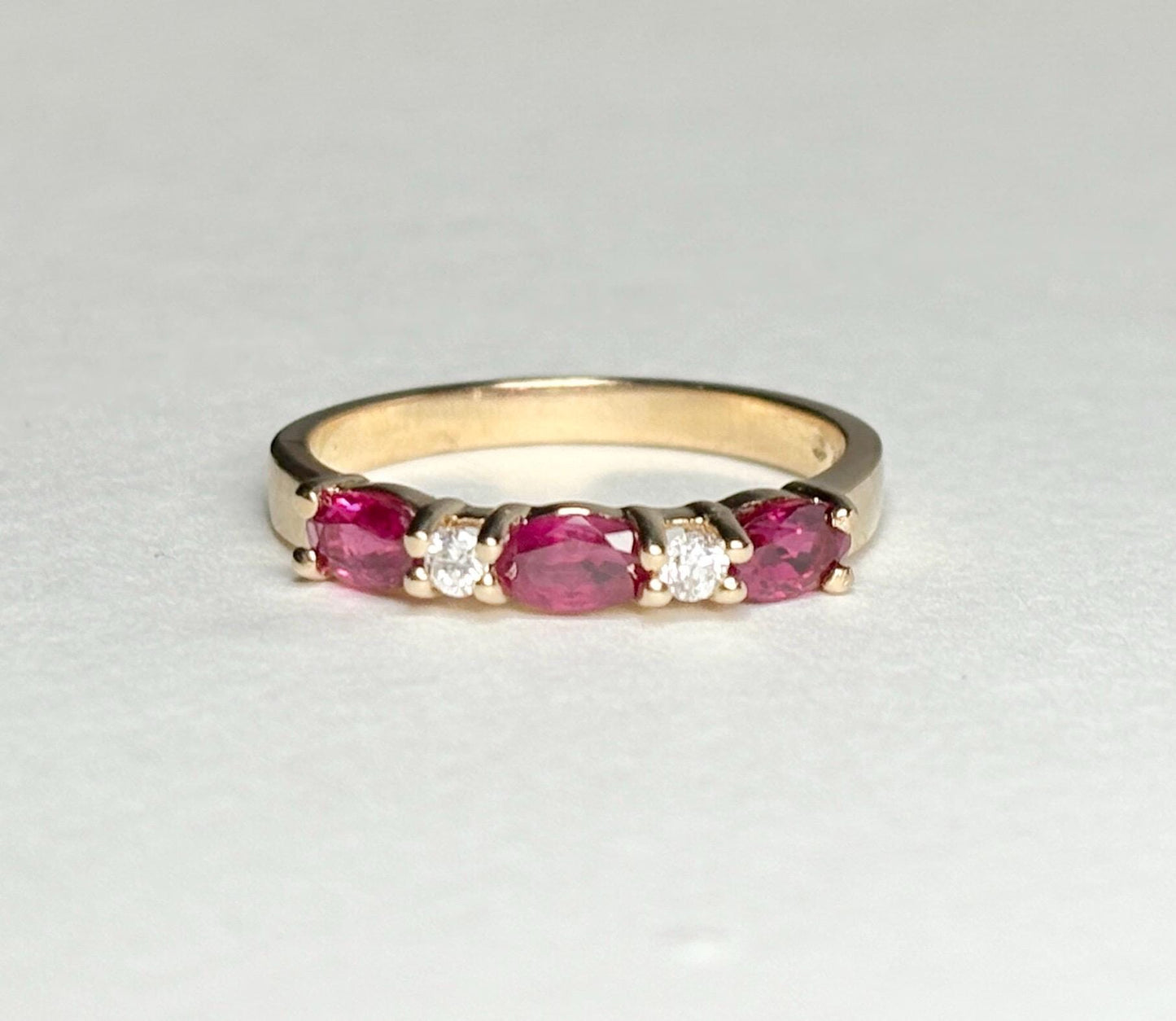A 14k gold band ring with oval rubies and diamonds.