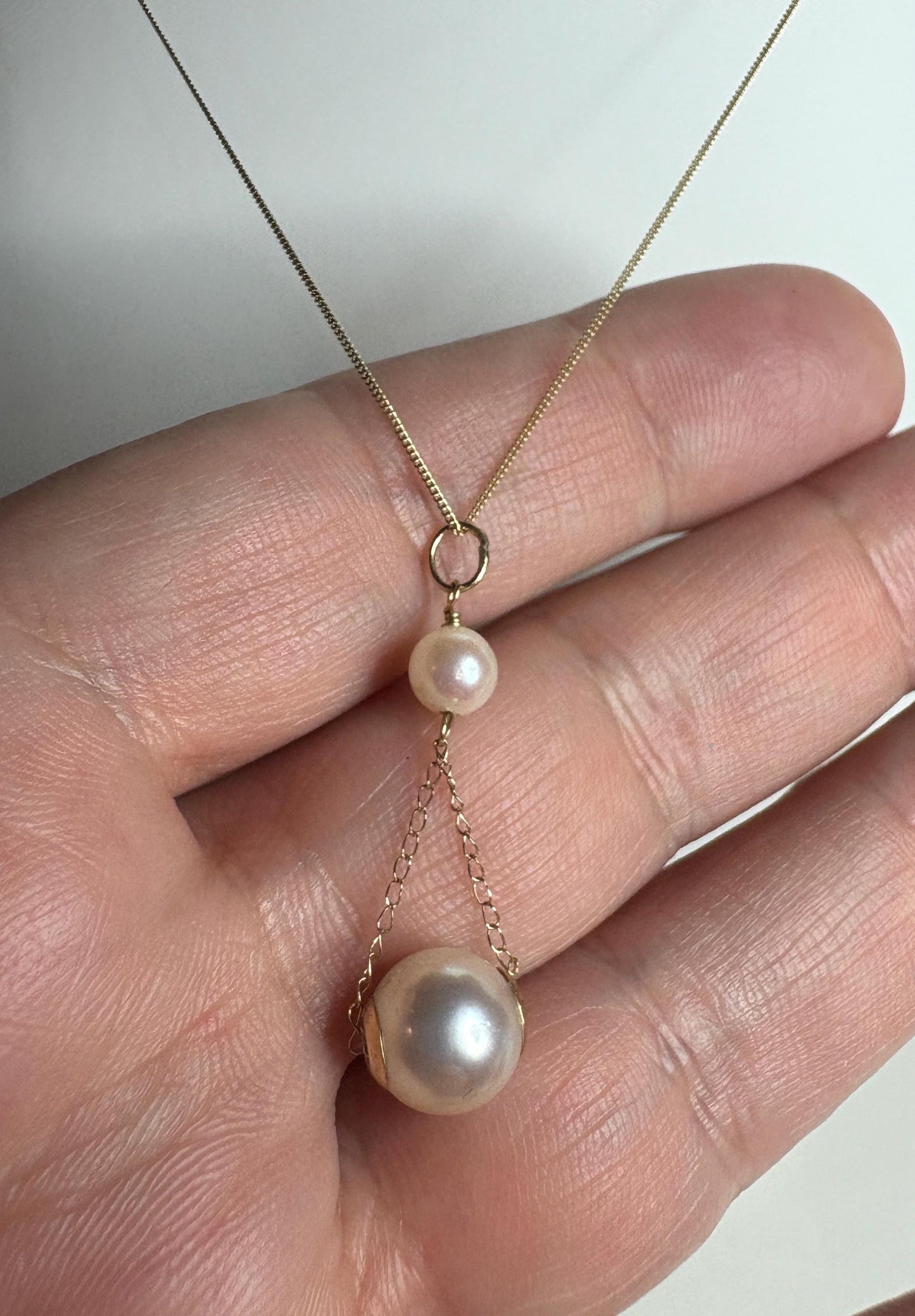 A gold lavaliere pendant necklace with two Akoya cultured pearls.