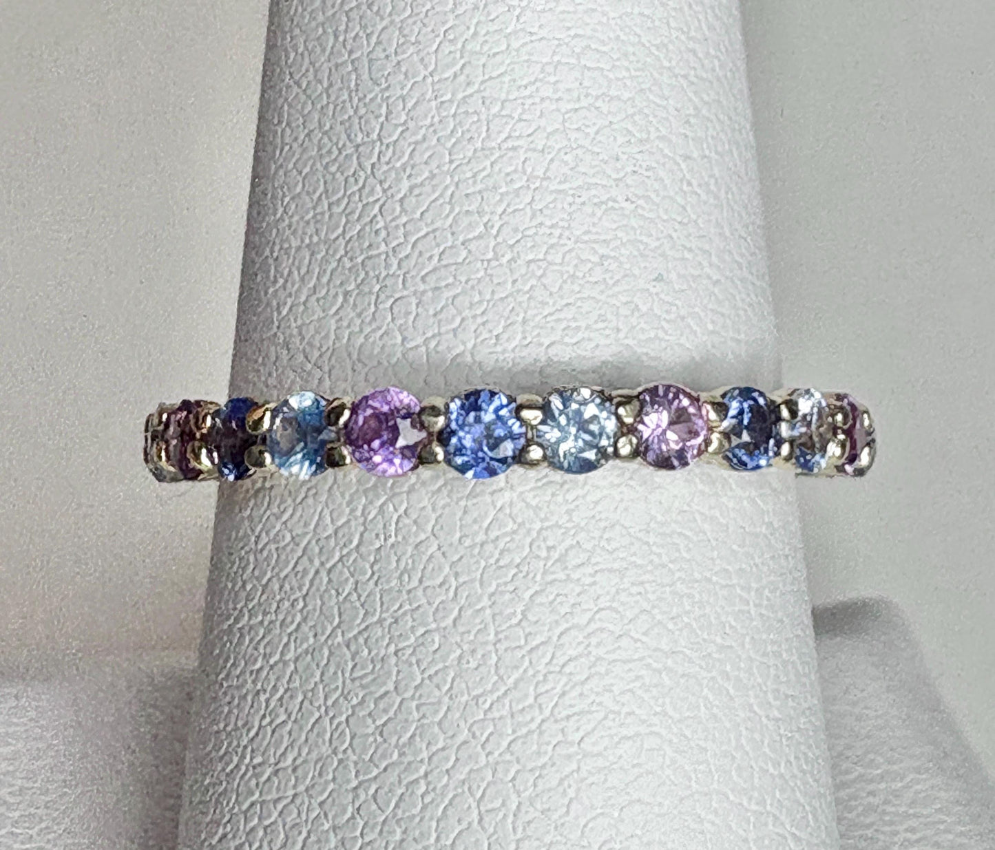 A 14k gold eternity band with multi-colored natural sapphires.