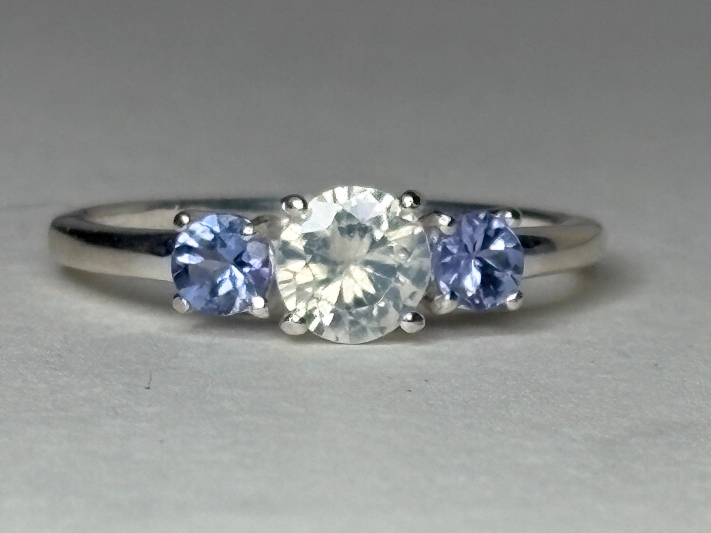 Sterling silver ring with a central off-white zircon and two tanzanite stones.