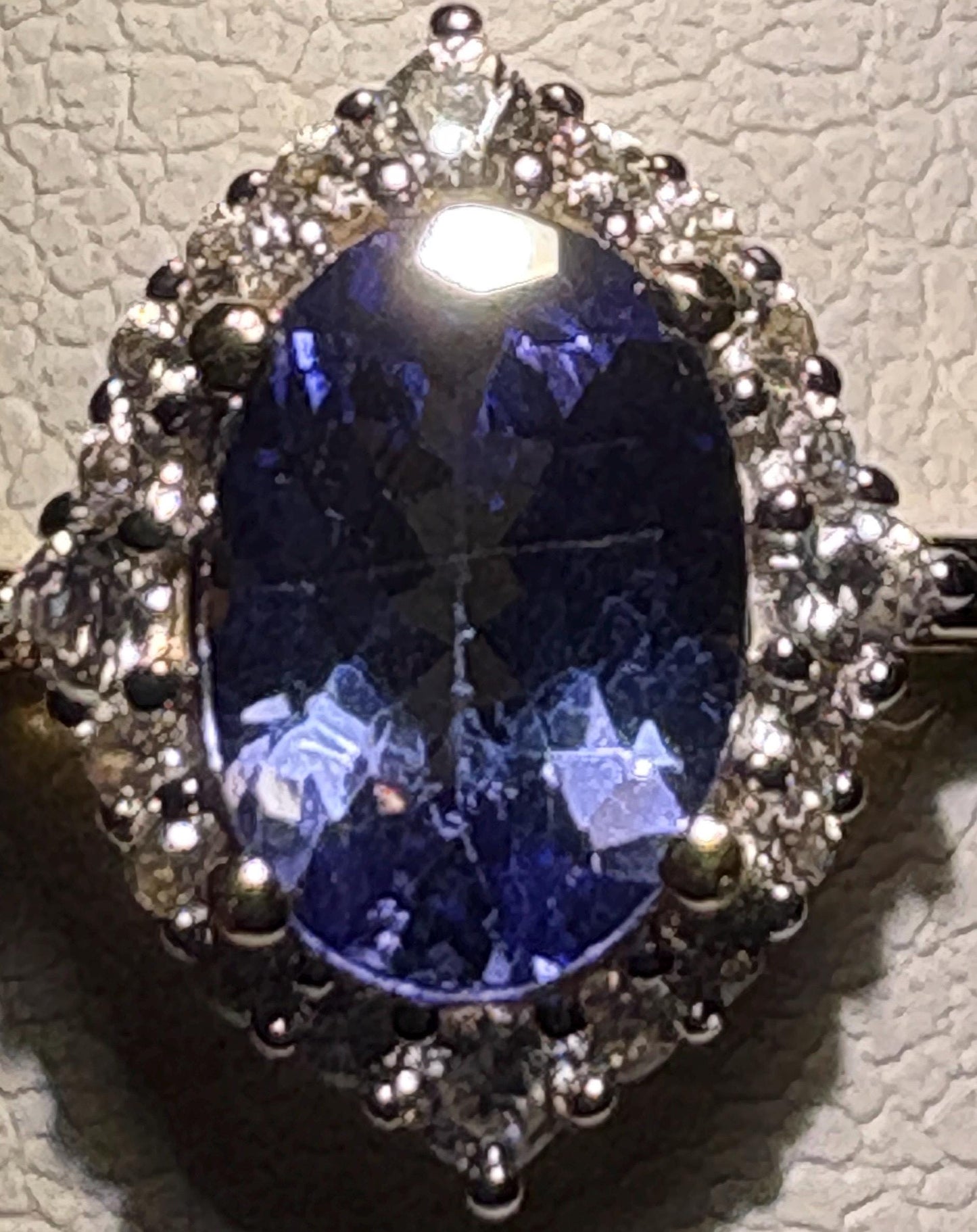 Oval tanzanite ring with zircon halo in 9k gold.