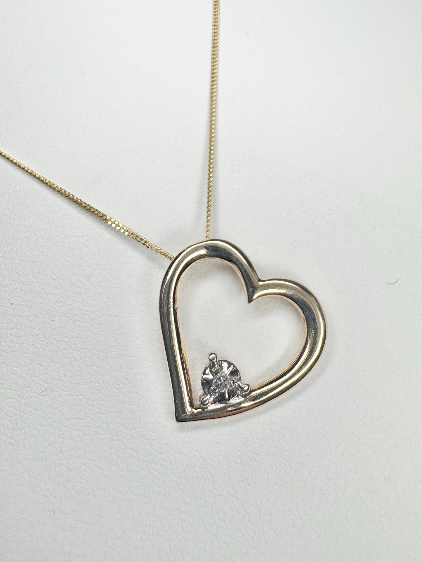 A gold heart pendant with a diamond on an 18-inch gold chain.