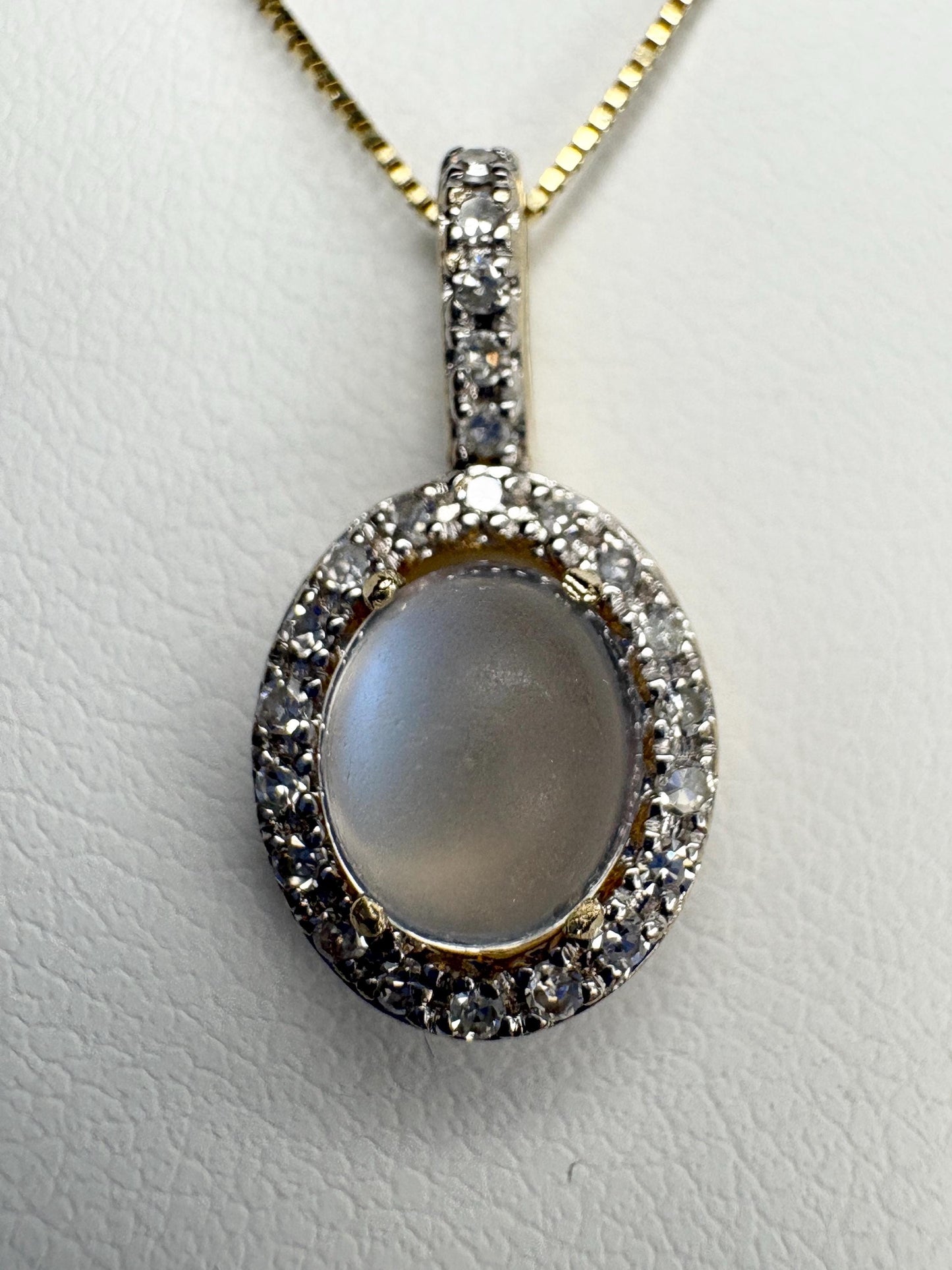 Oval blue sheen moonstone pendant with diamond halo on a 10k gold chain.