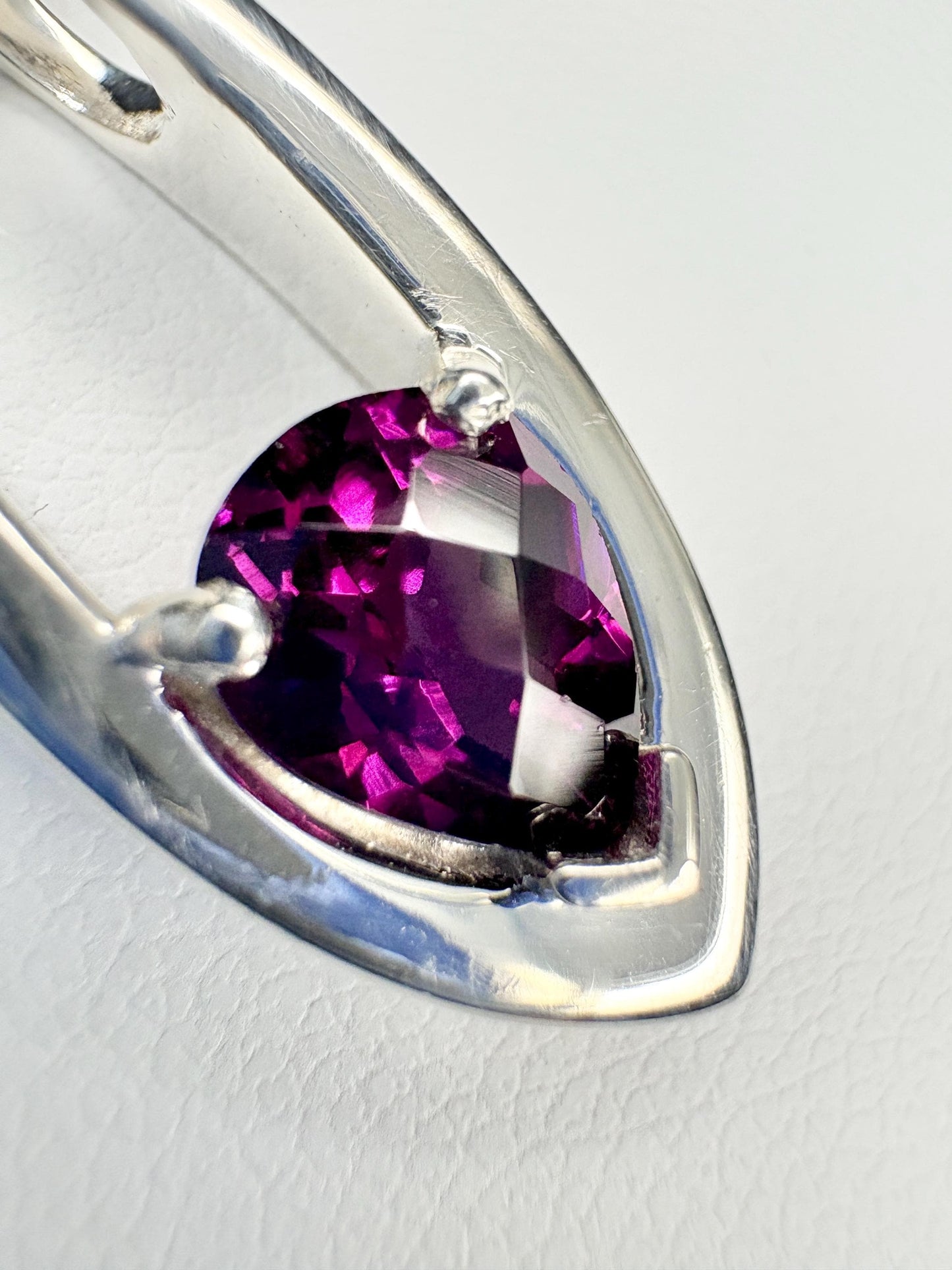 Sterling silver pendant with a pear-shaped, faceted grape rhodolite garnet.