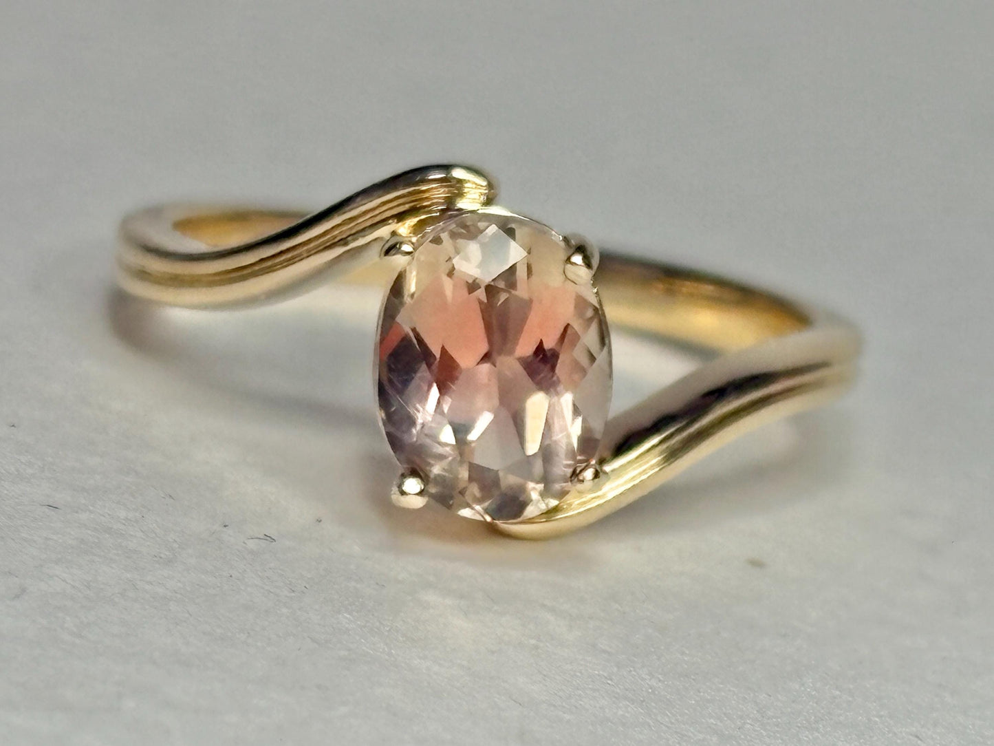 A 14k gold bypass ring with a light peach oval Oregon sunstone.