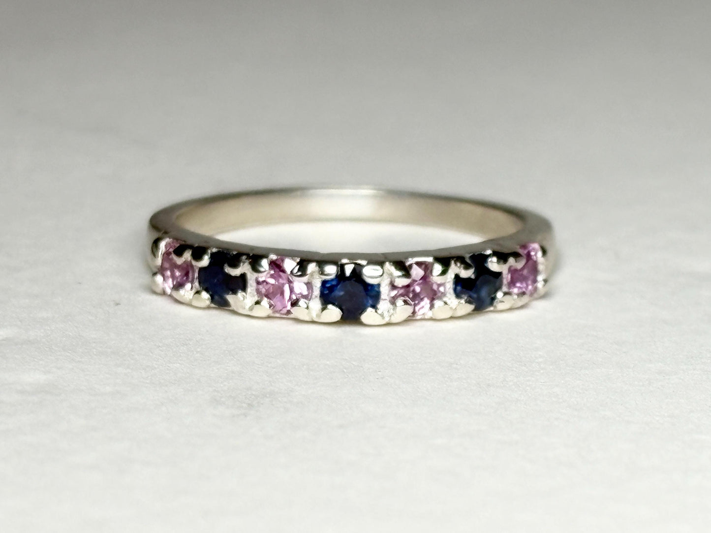 Sterling silver band ring with alternating blue and pink sapphires.