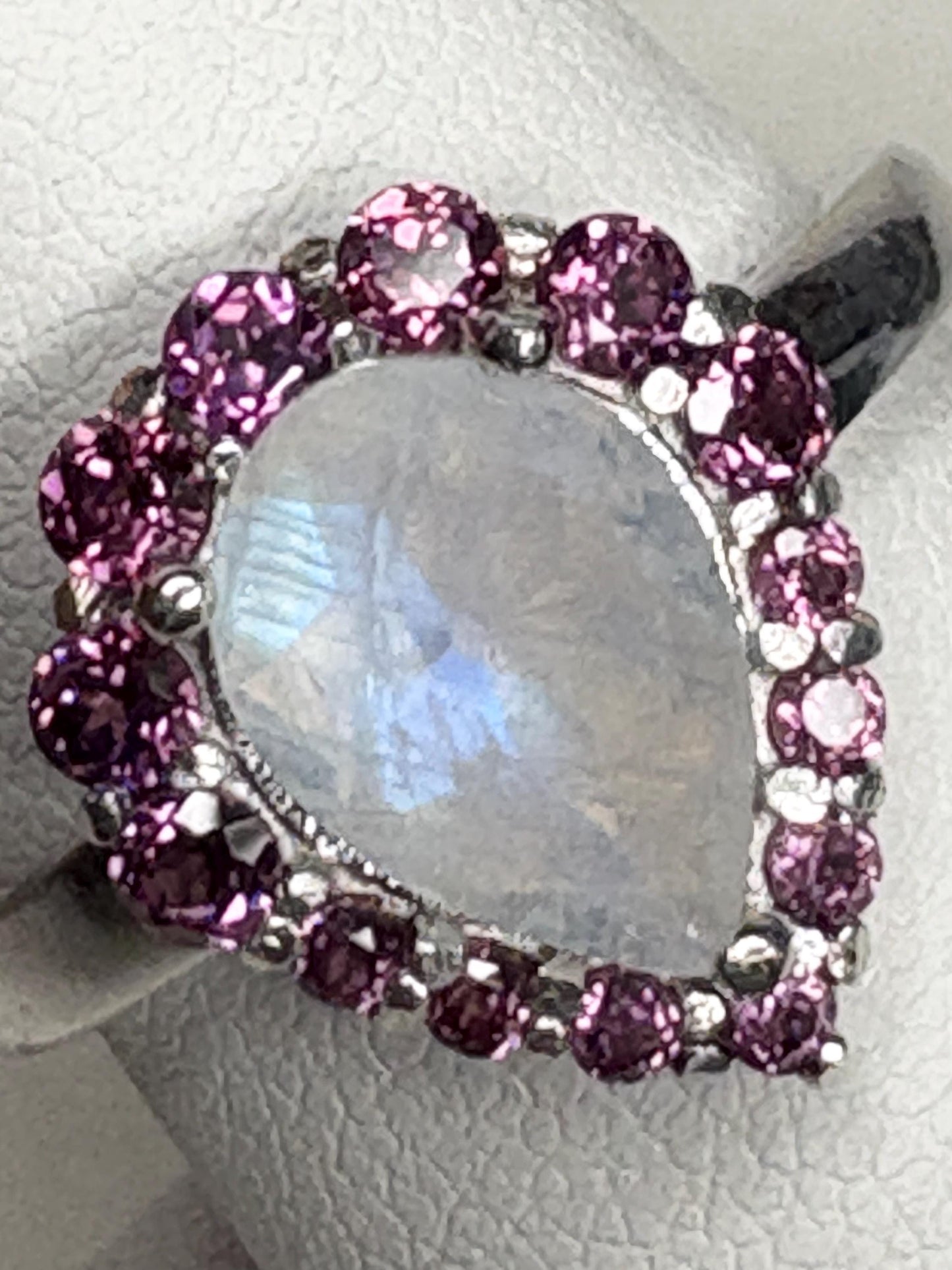 Sterling silver ring with a pear-shaped rainbow moonstone surrounded by rhodolite garnets.