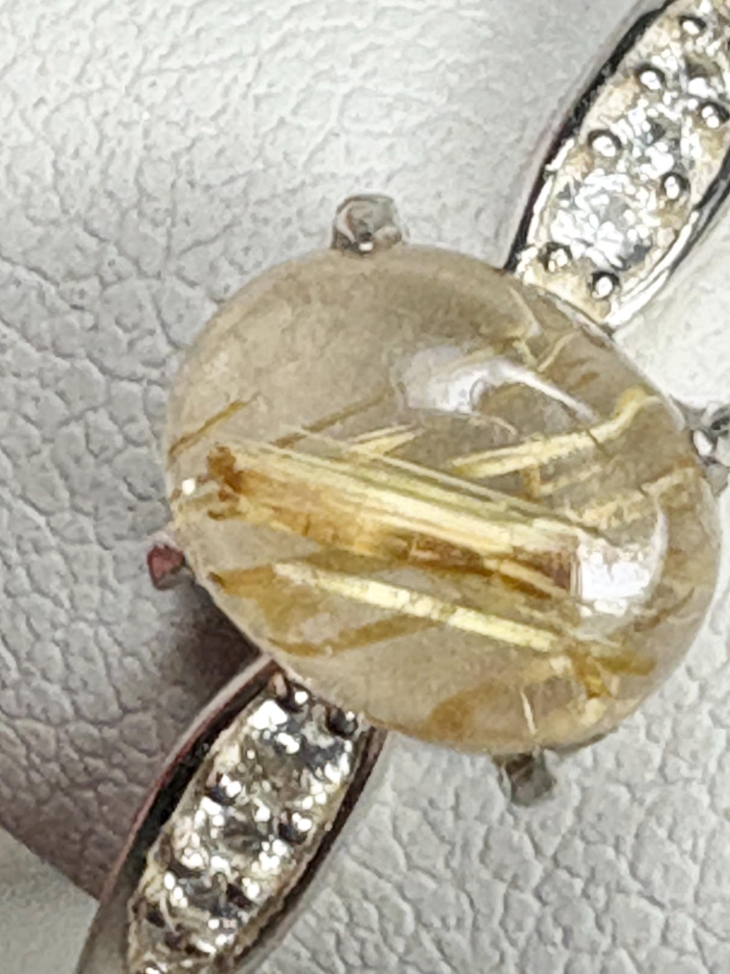 Sterling silver ring with a rutilated quartz cabochon and zircon accents.