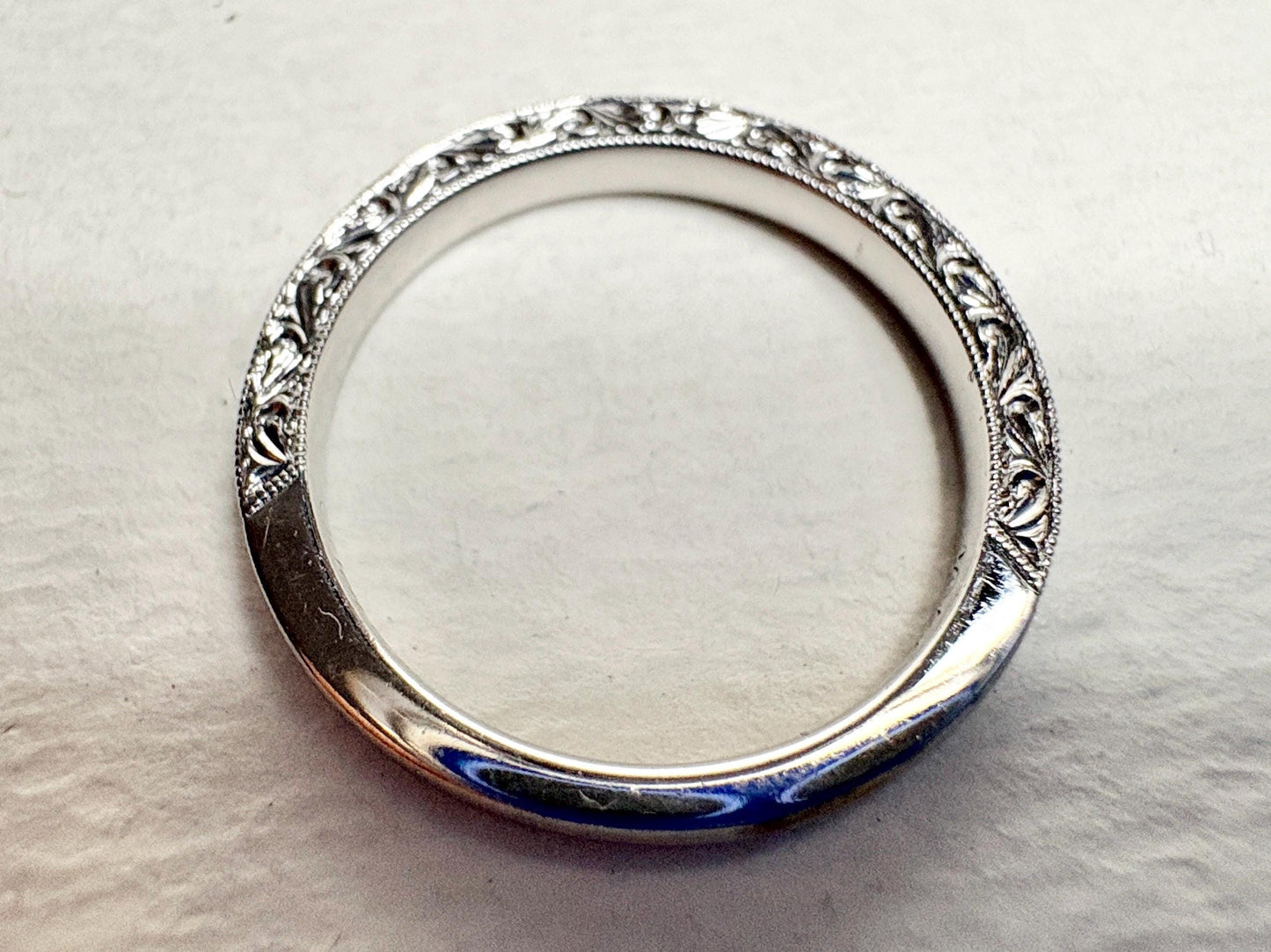 A white gold band ring with intricate detailing and diamonds.