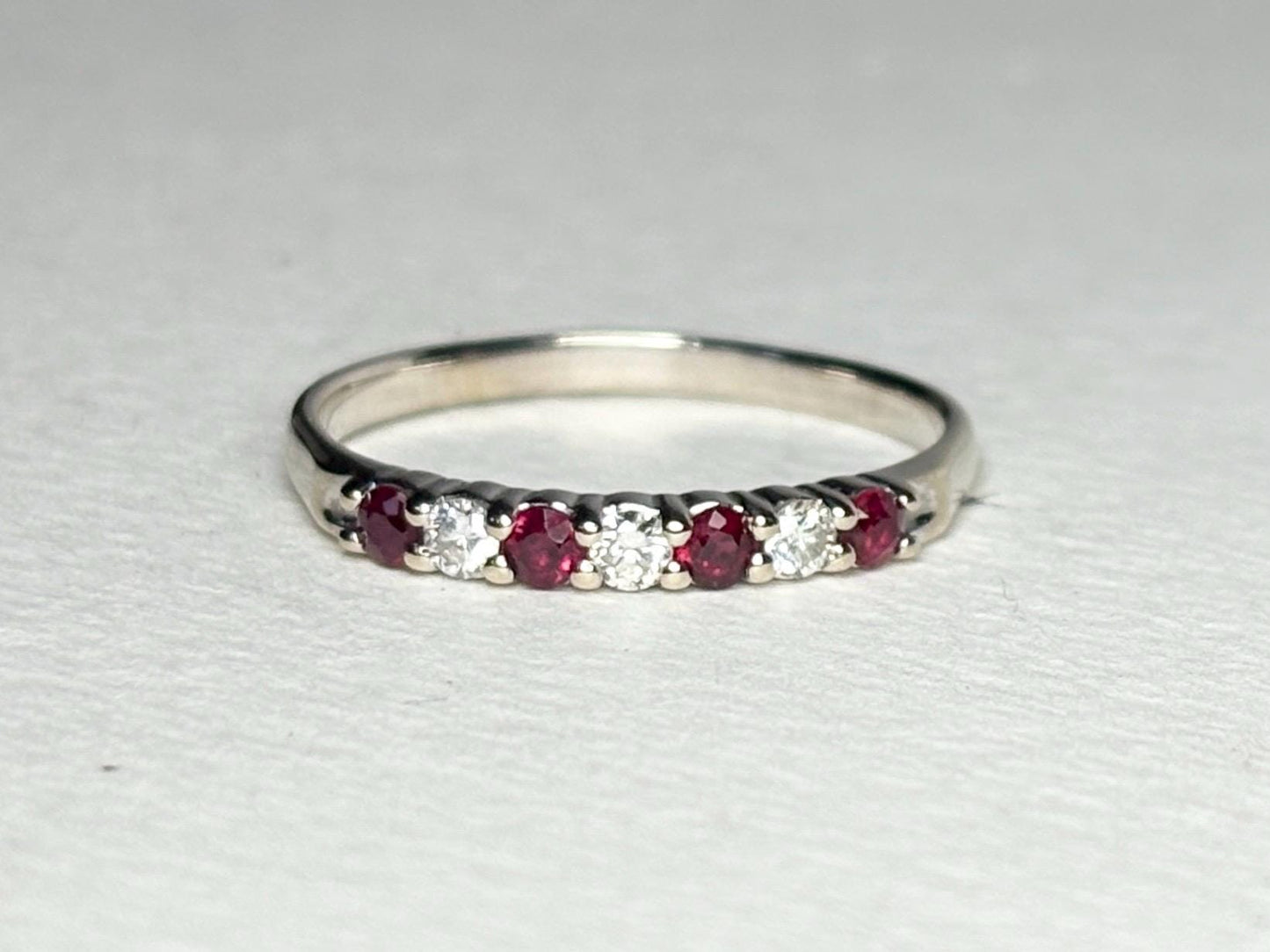 A white gold band ring with alternating rubies and diamonds.