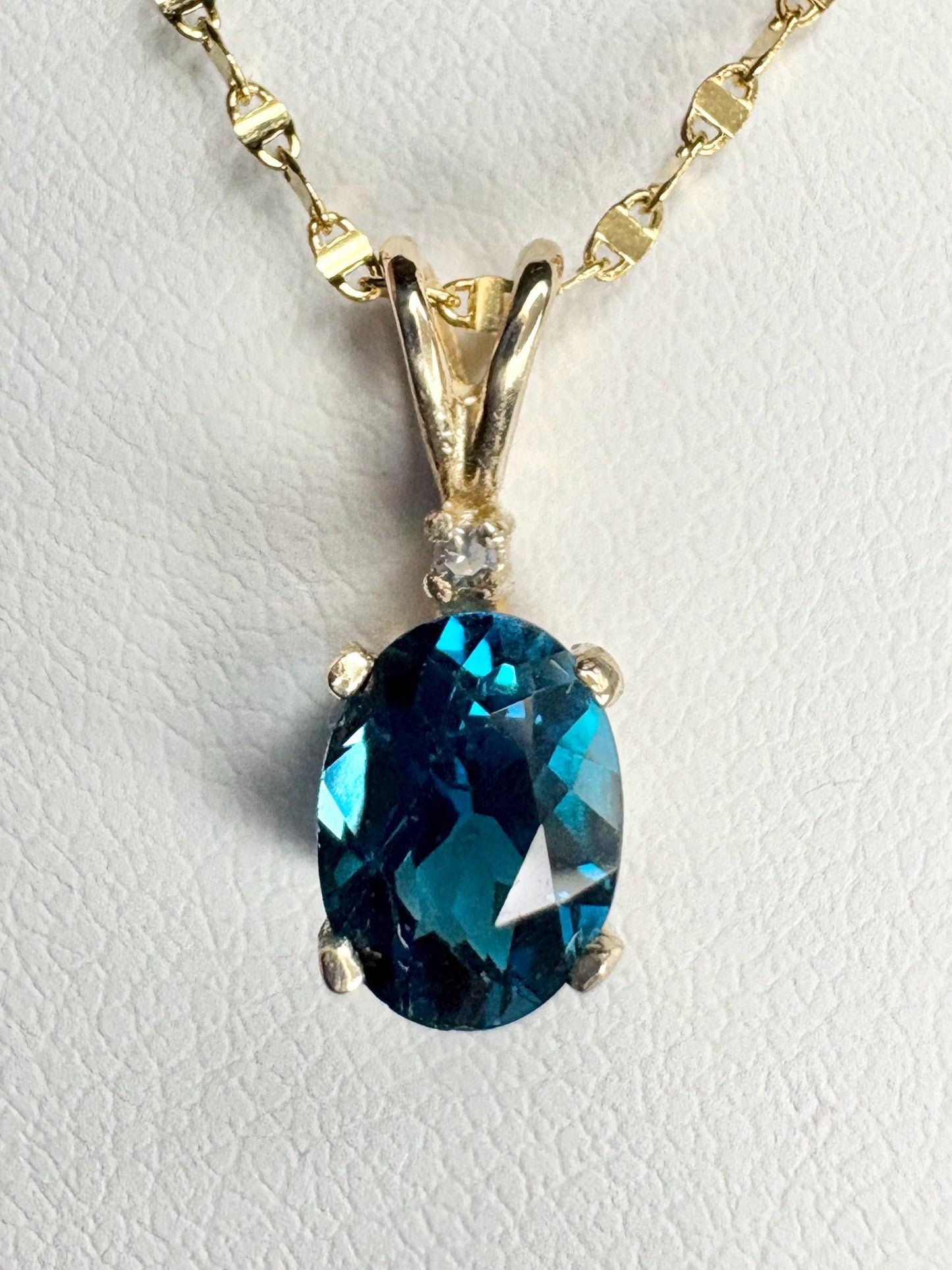 Oval London blue topaz pendant necklace with diamond accent on 14k gold chain.