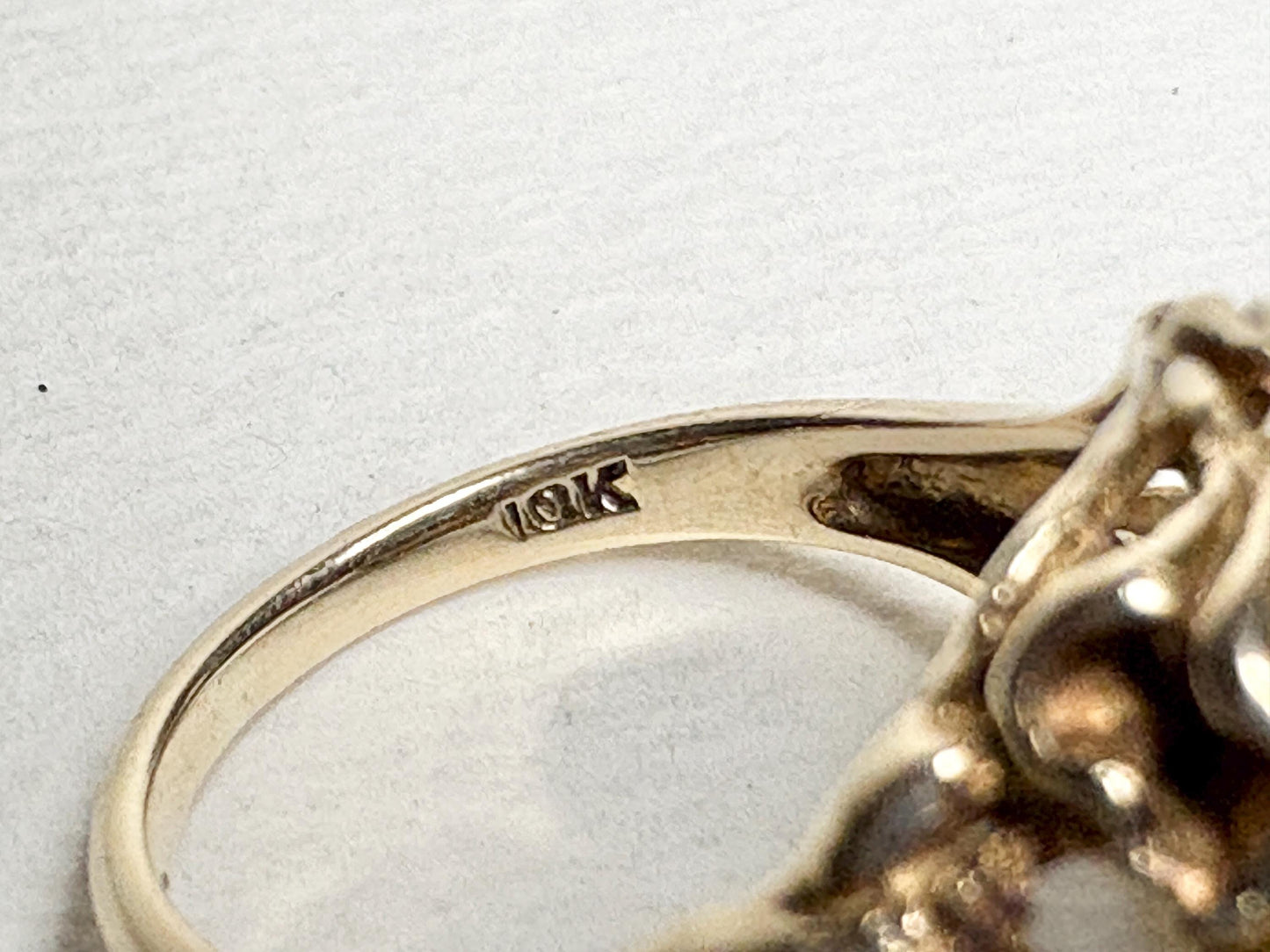 A 10k gold ring with a synthetic spinel and floral details.