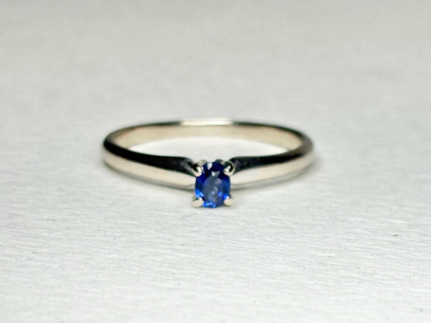 A vivid violetish blue oval sapphire solitaire in a 14k white gold ring.