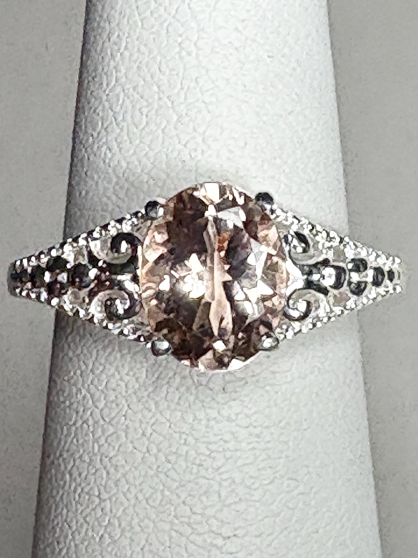 Sterling silver ring with an oval morganite gemstone and ornate detailing.
