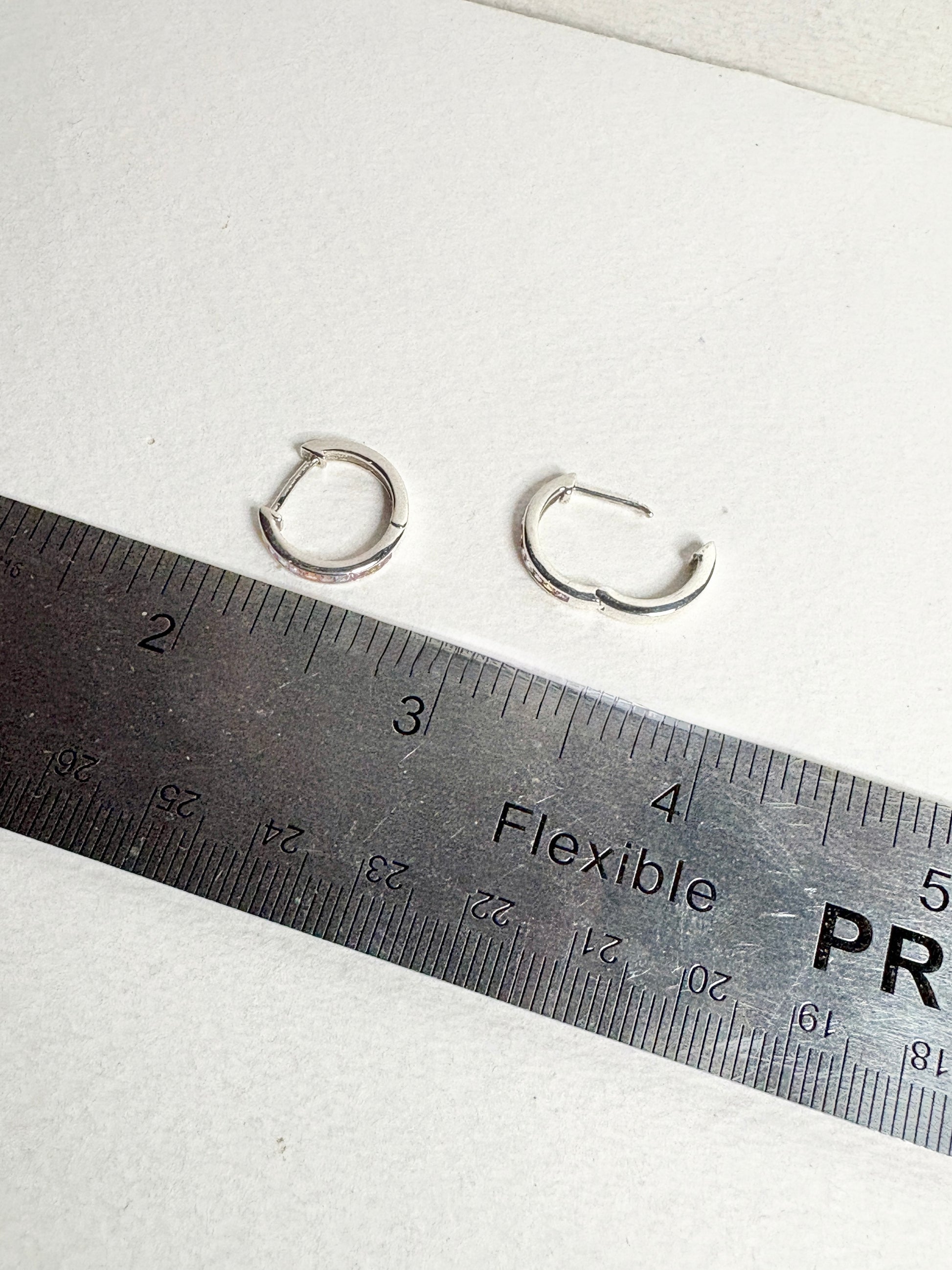 Sterling silver huggie hoop earrings with princess-cut multi-color sapphires.