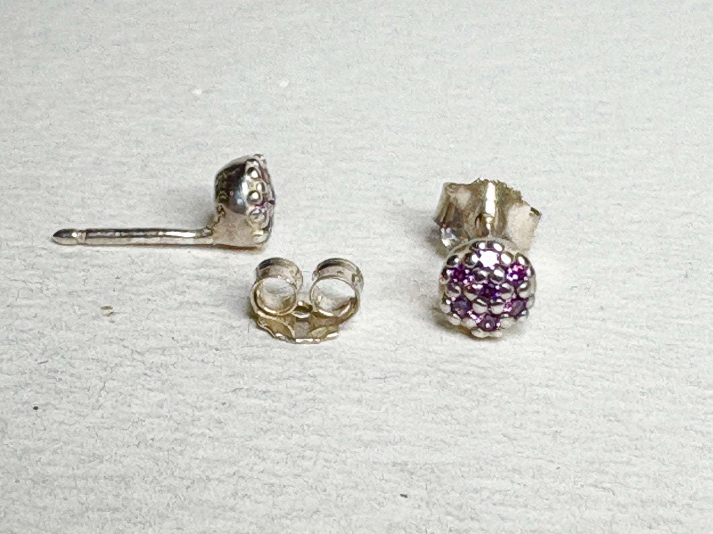 Sterling silver stud earrings with pave-set violet purple cubic zirconia stones.