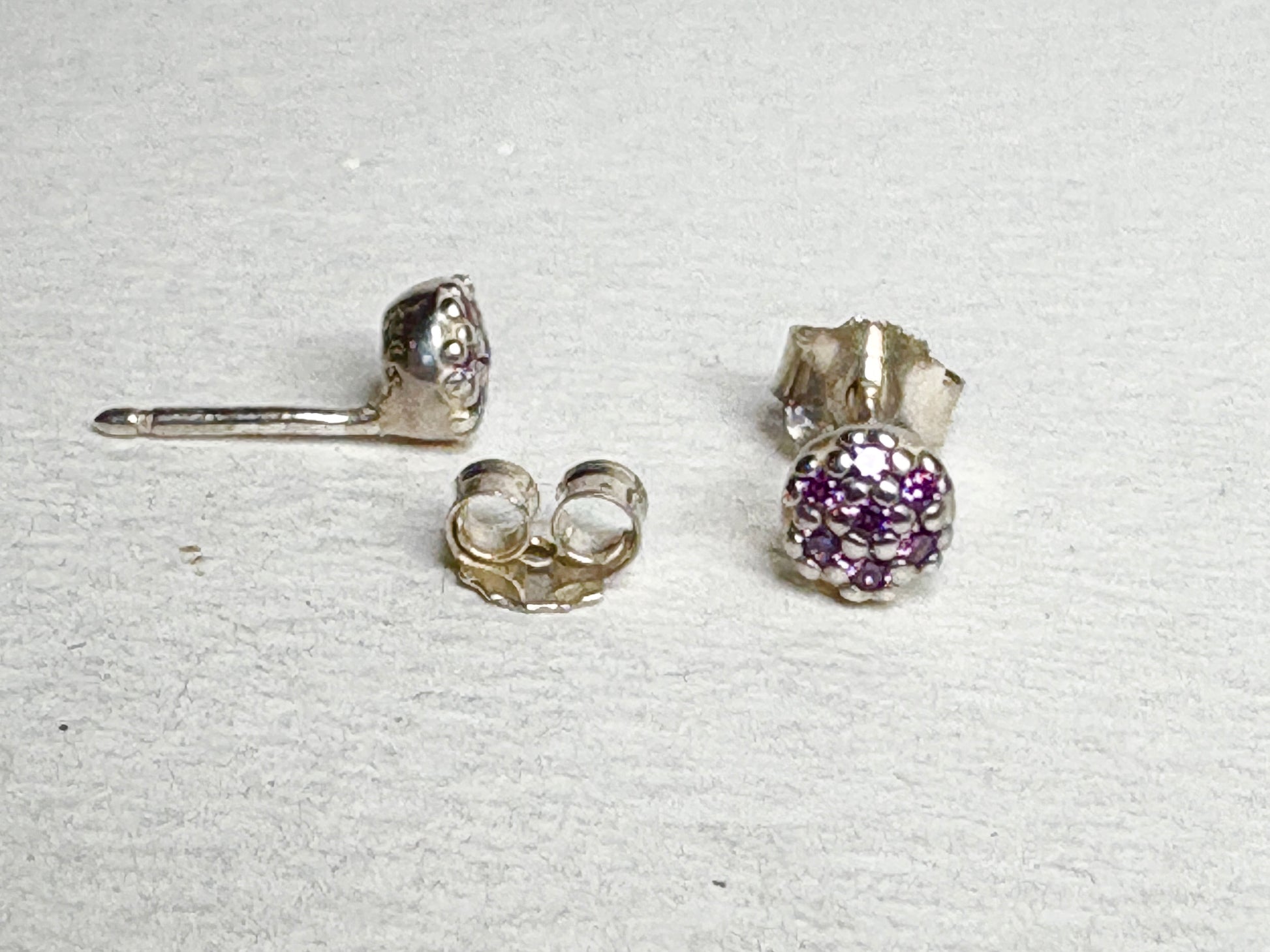 Sterling silver stud earrings with pave-set violet purple cubic zirconia stones.