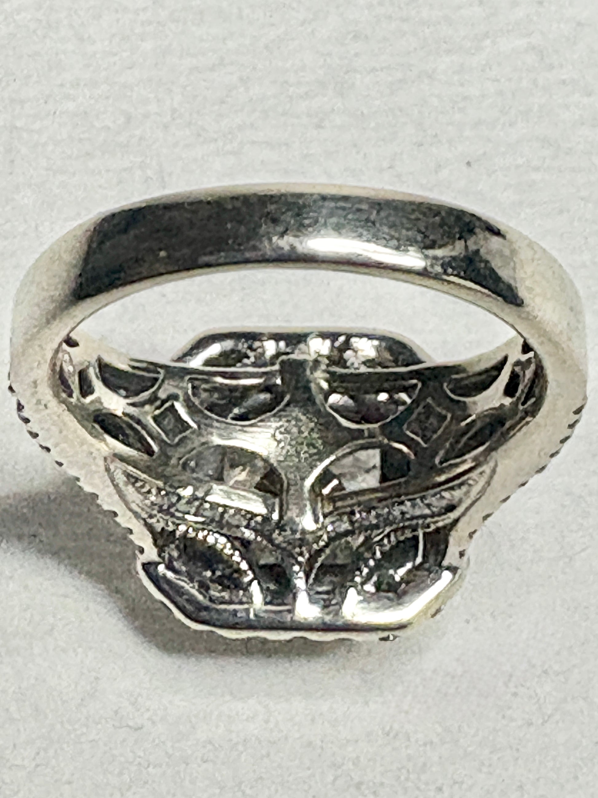 Silver ring with intricate detailing and a central stone.