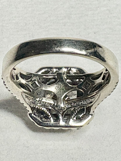 Silver ring with intricate detailing and a central stone.
