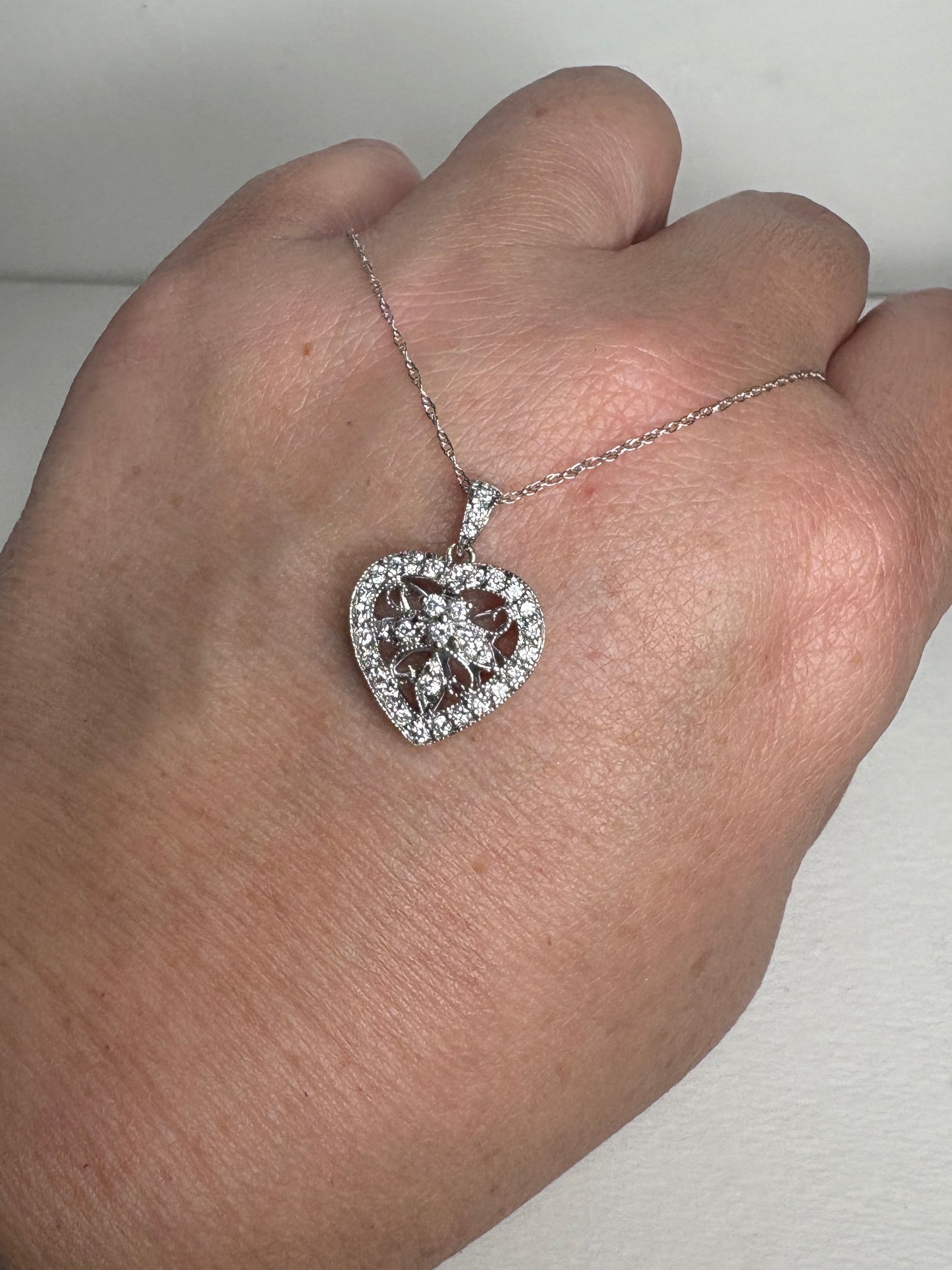 A diamond-encrusted heart pendant necklace on a thin white gold chain.
