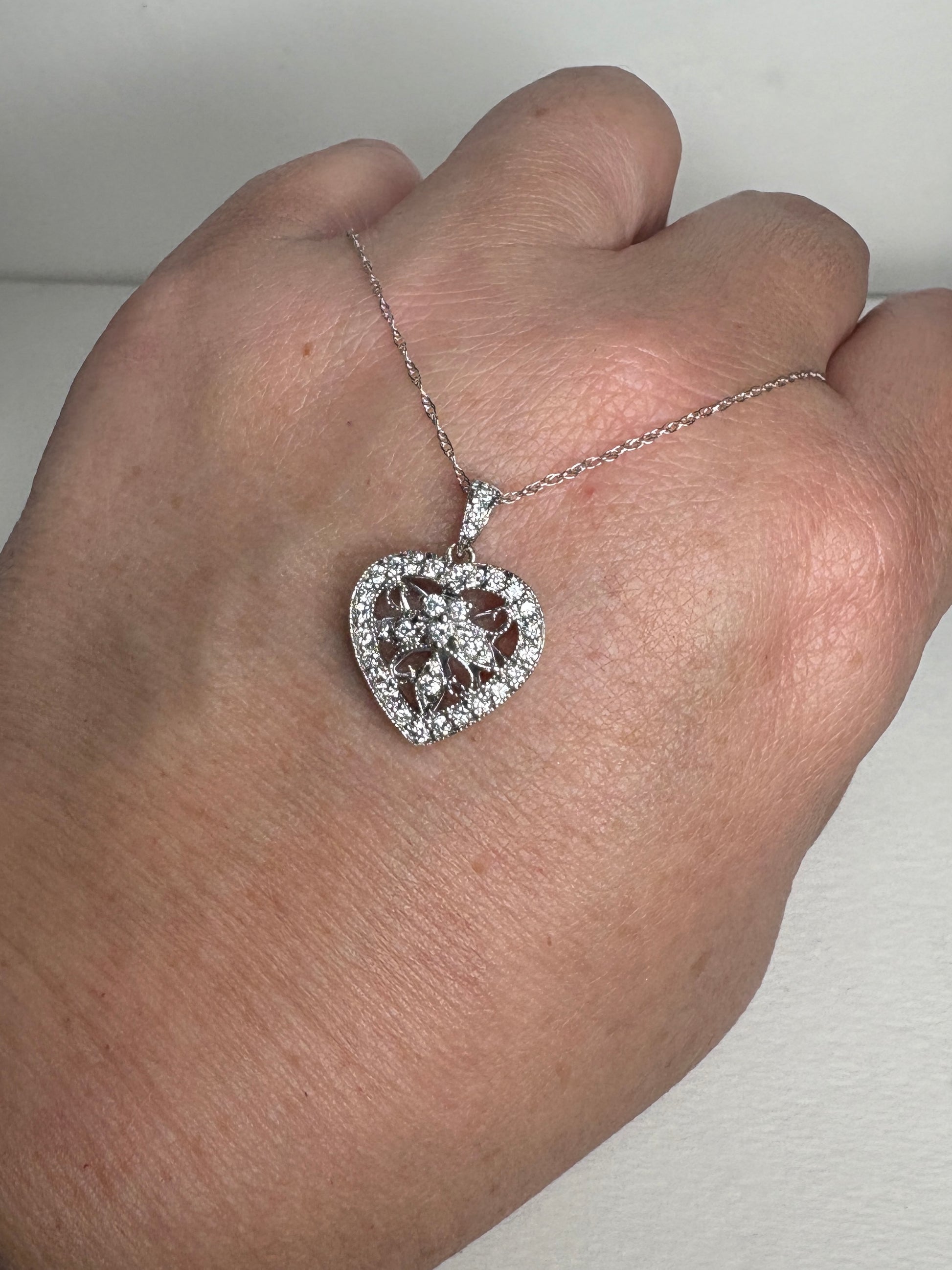 A diamond-encrusted heart pendant necklace on a thin white gold chain.