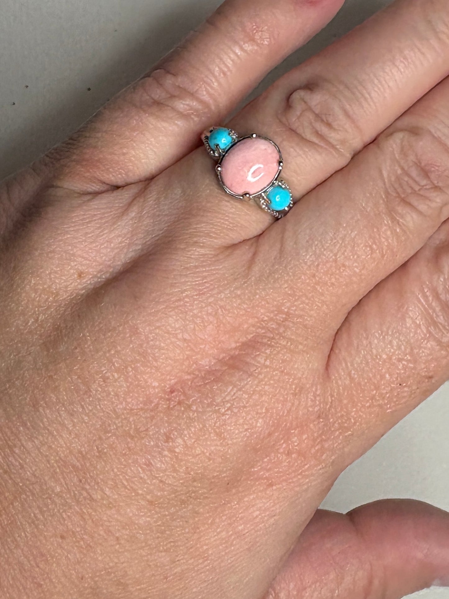 Sterling silver ring with oval peach opal and two round turquoise stones.
