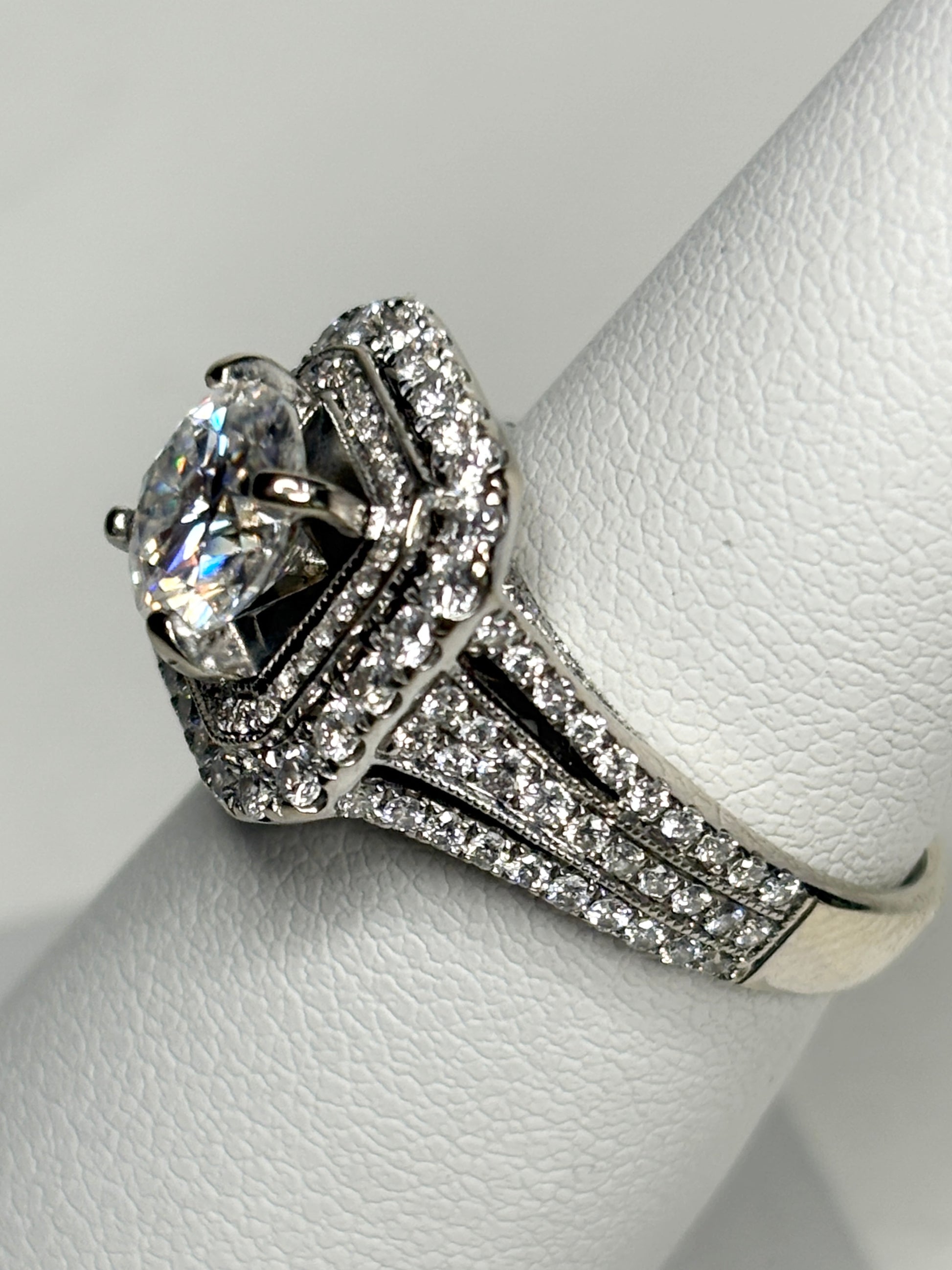 A 14k white gold ring with a large center stone and a double halo of diamonds.