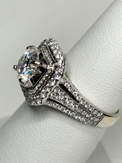 A 14k white gold ring with a large center stone and a double halo of diamonds.
