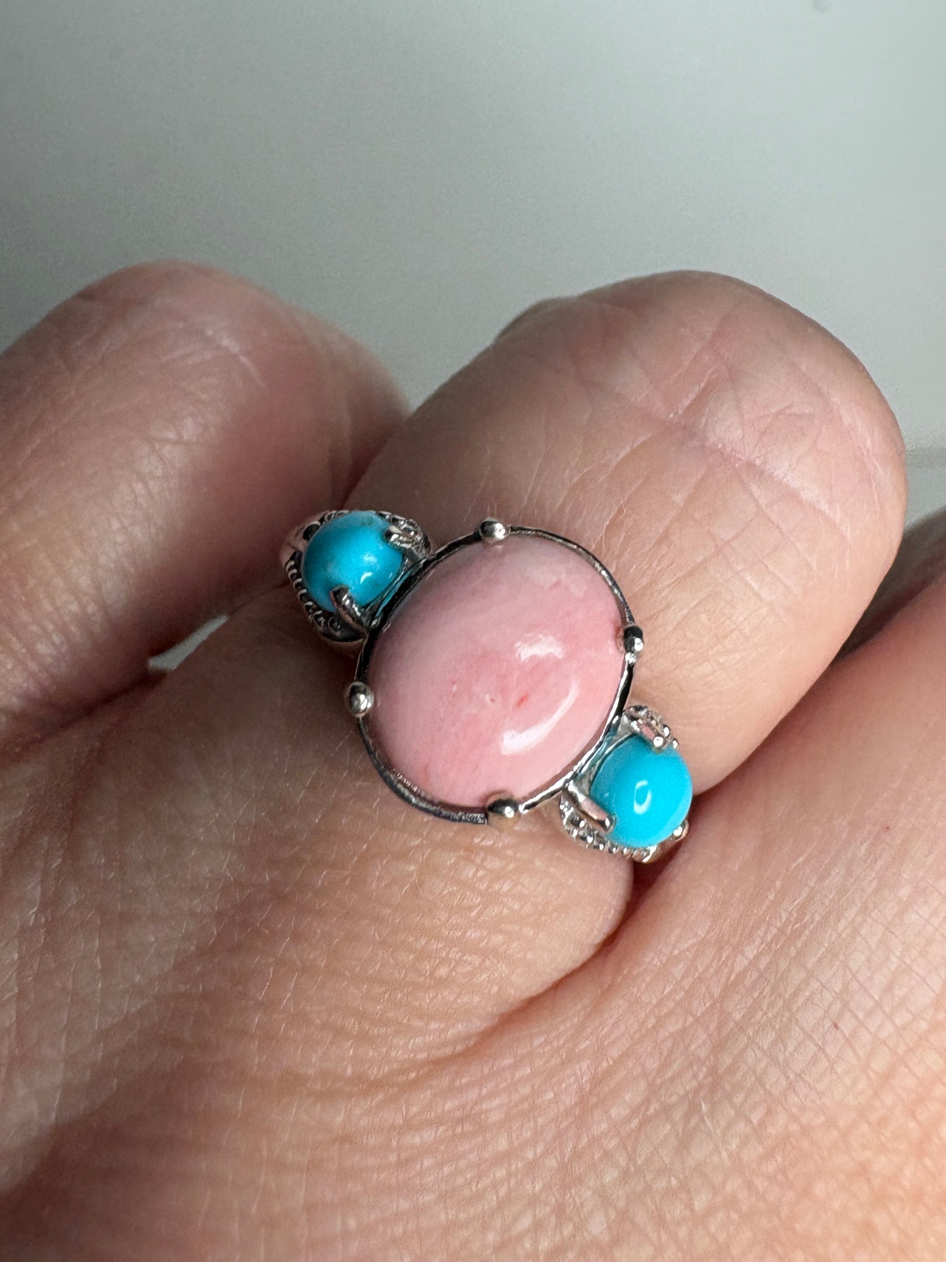 Sterling silver ring with oval peach opal and two round turquoise cabochons.