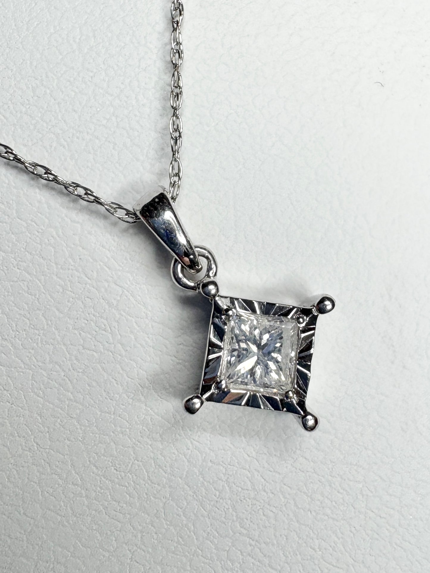 A princess cut diamond pendant necklace on a 10k white gold rope chain.