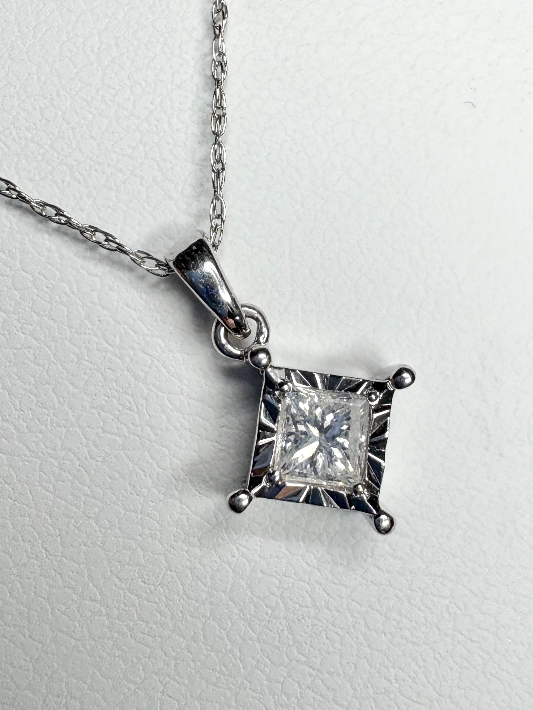 A princess cut diamond pendant necklace on a 10k white gold rope chain.