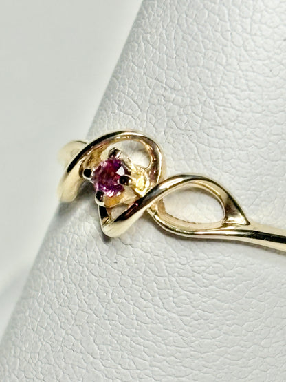 A 10k gold ribbon style ring with a pink bixbite gemstone.