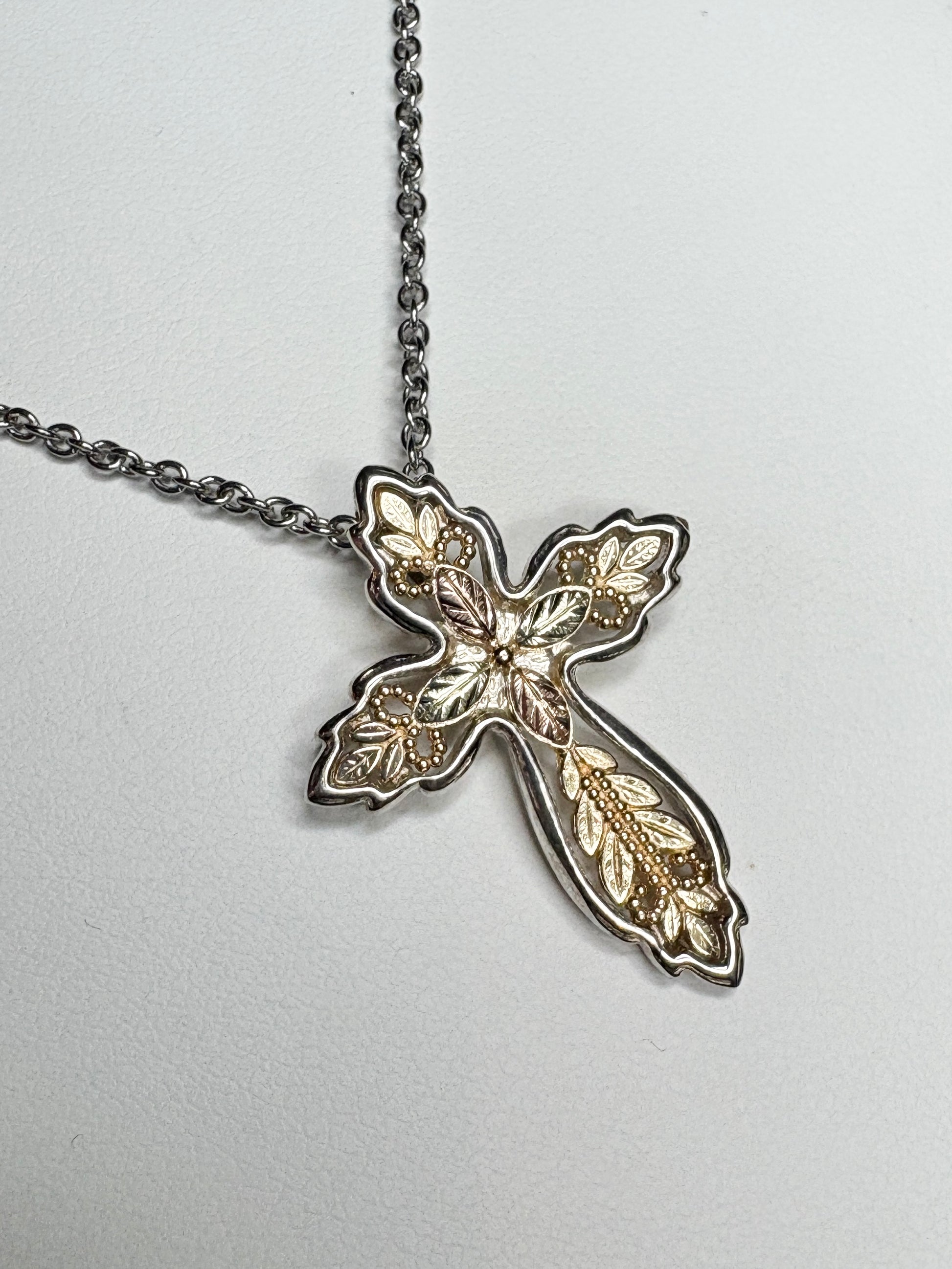 Black Hills Gold ornate cross pendant with sterling silver frame and stainless steel chain.