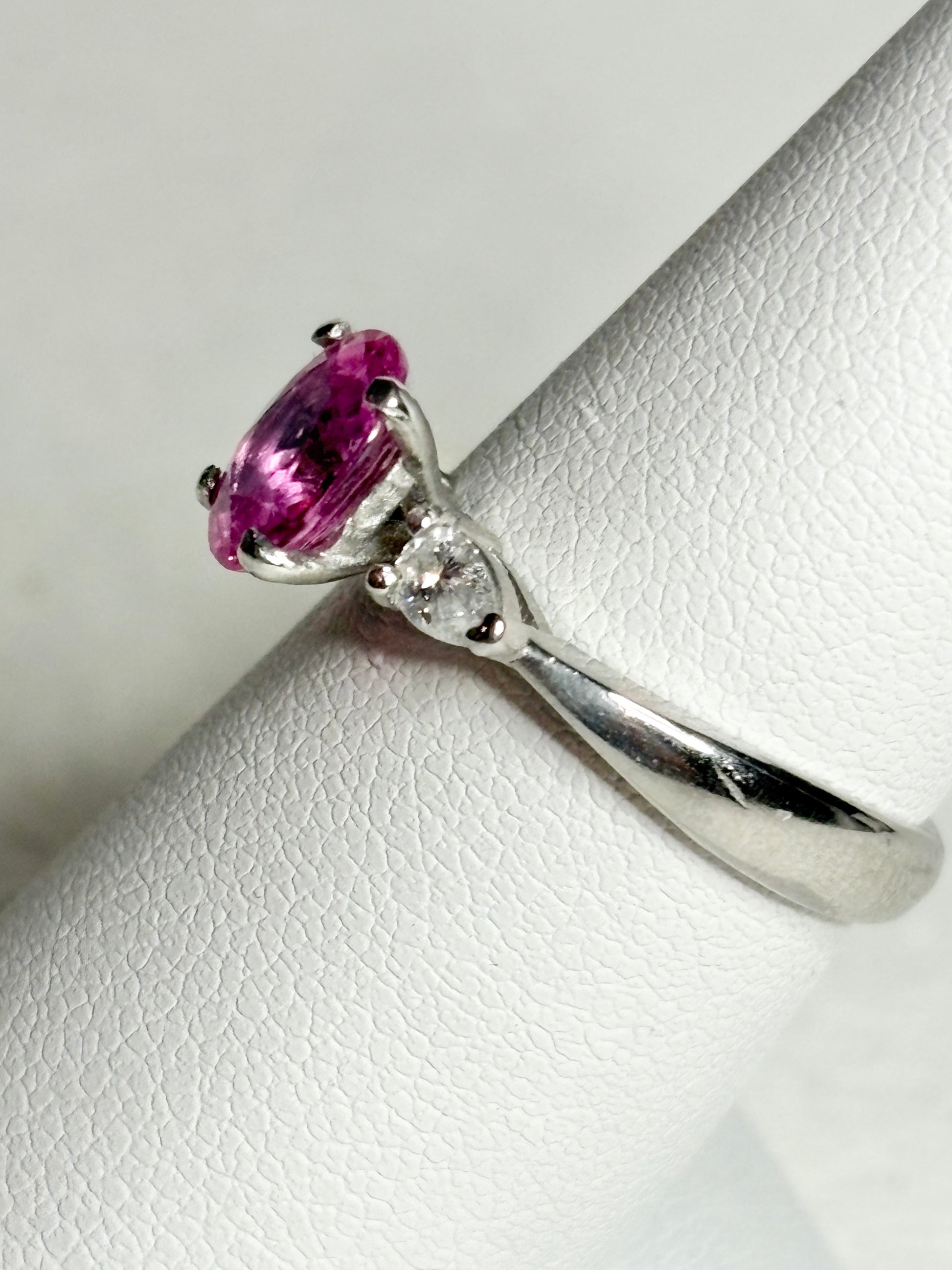 Platinum ring with a pink sapphire and two pear-shaped diamonds.