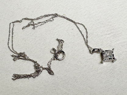 A 10k white gold pendant necklace with a princess cut diamond on a thin rope chain.