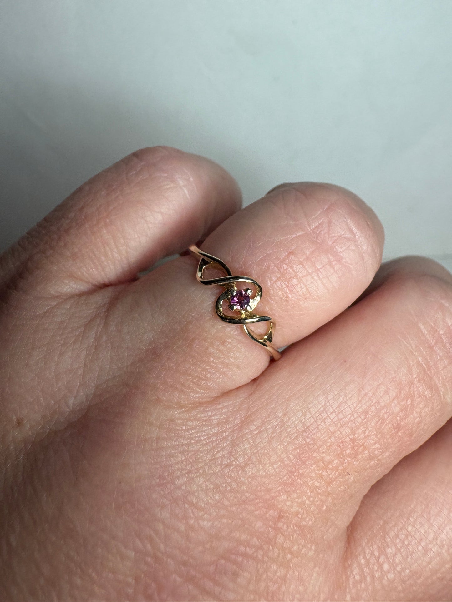 A 10k gold ribbon ring with a pink bixbite gemstone.