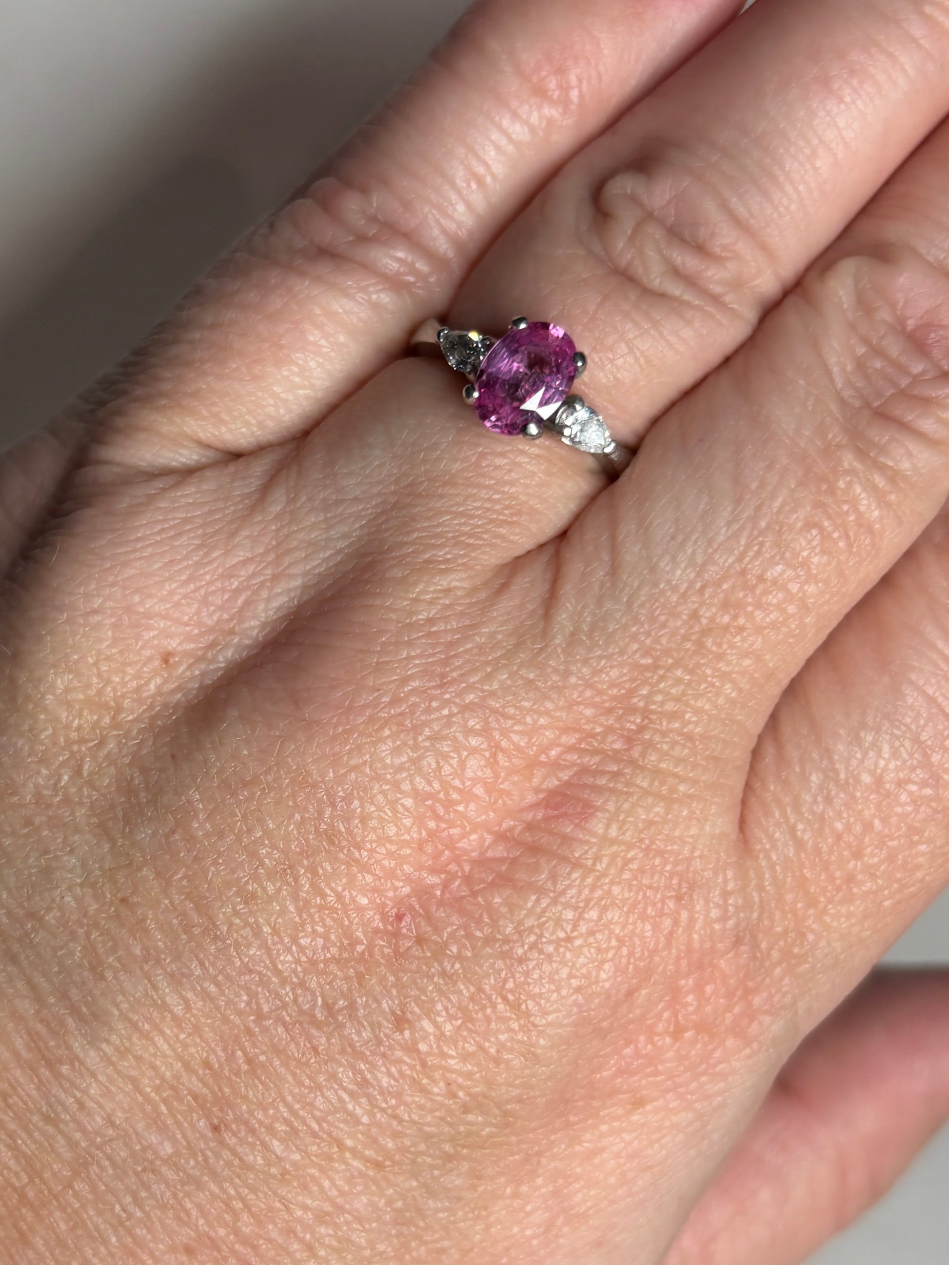 Platinum ring with oval pink sapphire and pear-shaped diamonds.