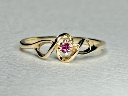 A 10k gold ribbon ring with a pink bixbite gemstone.